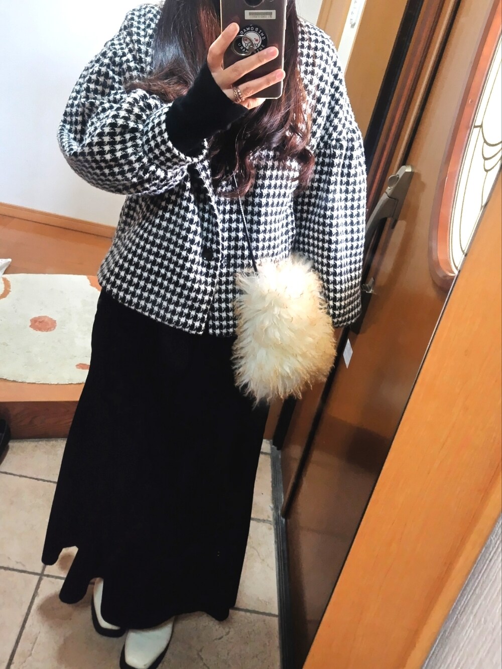 ブラック系のノーカラーコート、ブラック系のスカート、ホワイト系のブーツを着用したレディースの春コーディネートの2枚目の写真