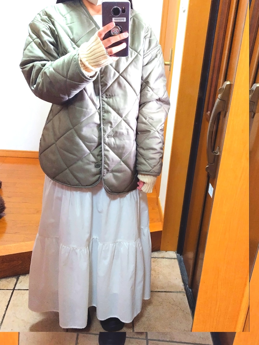 ブラウン系のベスト、グリーン系のノーカラージャケット、ホワイト系のショルダーバッグを着用したレディースの冬コーディネートの3枚目の写真