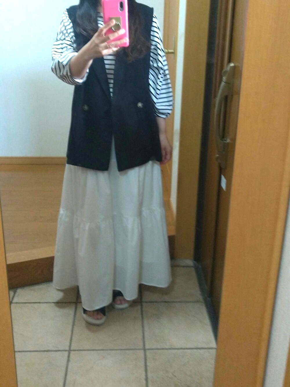 ブラック系のベスト、ブラック系のTシャツ/カットソー、ブラック系のショルダーバッグを着用したレディースの春コーディネートの2枚目の写真