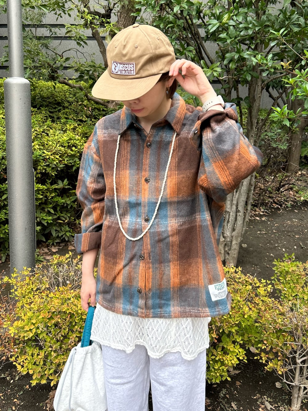 オレンジ系のシャツ/ブラウス、ホワイト系のキャミソール、グレー系のスウェットパンツを着用したレディースの秋コーディネートの4枚目の写真