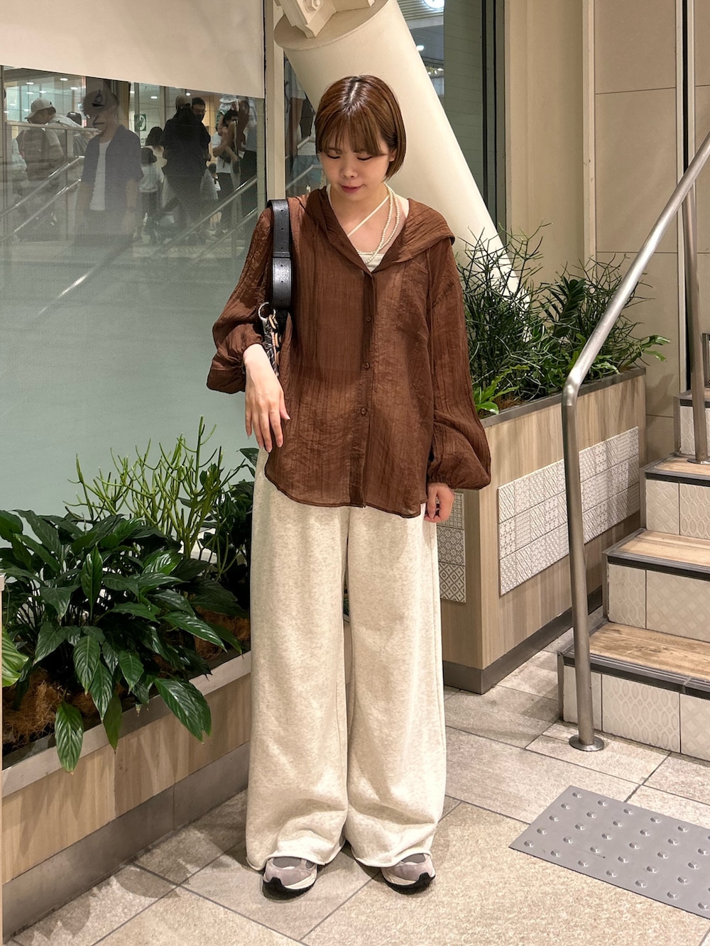 ブラック系のショルダーバッグ、ブラウン系のシャツ/ブラウス、ホワイト系のスウェットパンツを着用したレディースの夏コーディネートの2枚目の写真