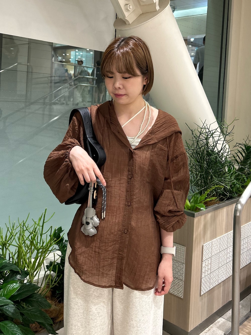 ブラック系のショルダーバッグ、ブラウン系のシャツ/ブラウス、ホワイト系のスウェットパンツを着用したレディースの夏コーディネートの5枚目の写真