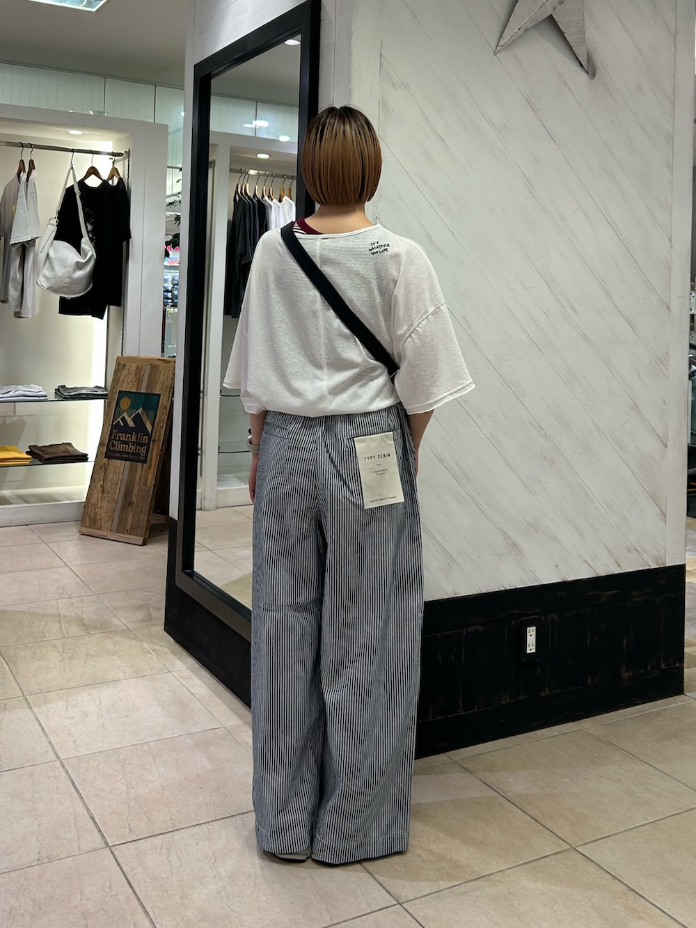 ブラック系のショルダーバッグ、ホワイト系のTシャツ/カットソー、ブルー系のデニムパンツを着用したレディースの夏コーディネートの3枚目の写真
