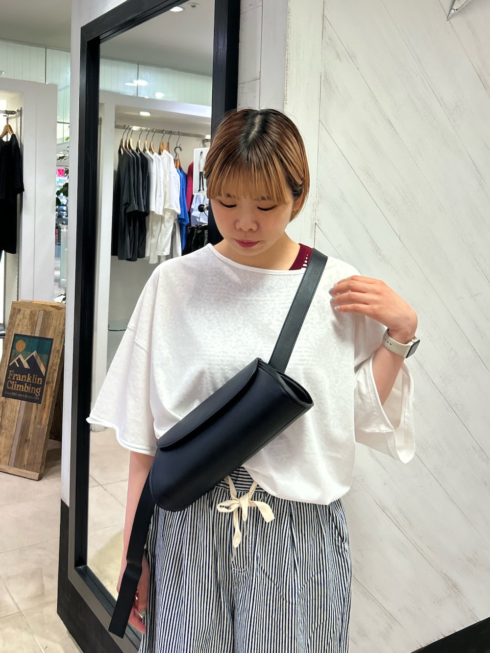 ブラック系のショルダーバッグ、ホワイト系のTシャツ/カットソー、ブルー系のデニムパンツを着用したレディースの夏コーディネートの4枚目の写真