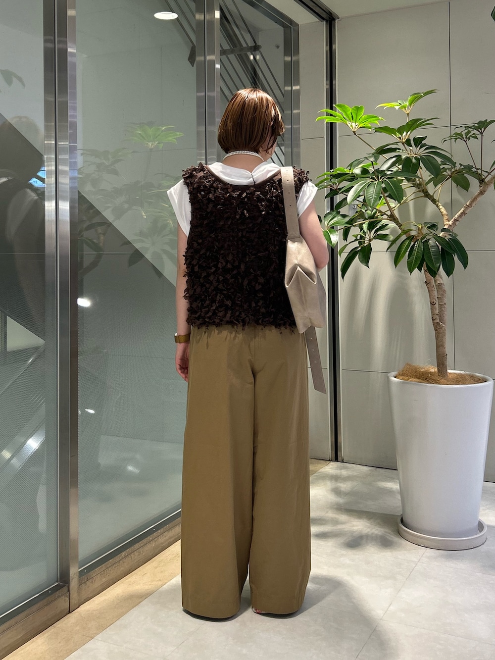 ベージュ系のデニムパンツ、ホワイト系のTシャツ/カットソー、ブラウン系のベストを着用したレディースの秋コーディネートの3枚目の写真