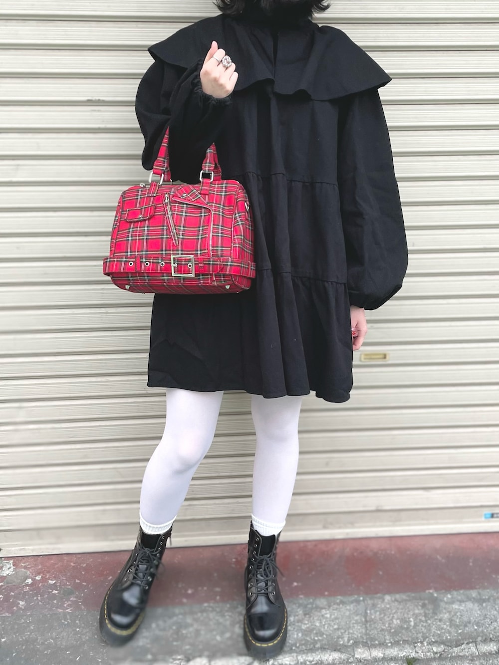 レッド系のハンドバッグ、ブラック系のワンピース/ドレス、ブラック系のブーツを着用したレディースの秋コーディネートの2枚目の写真