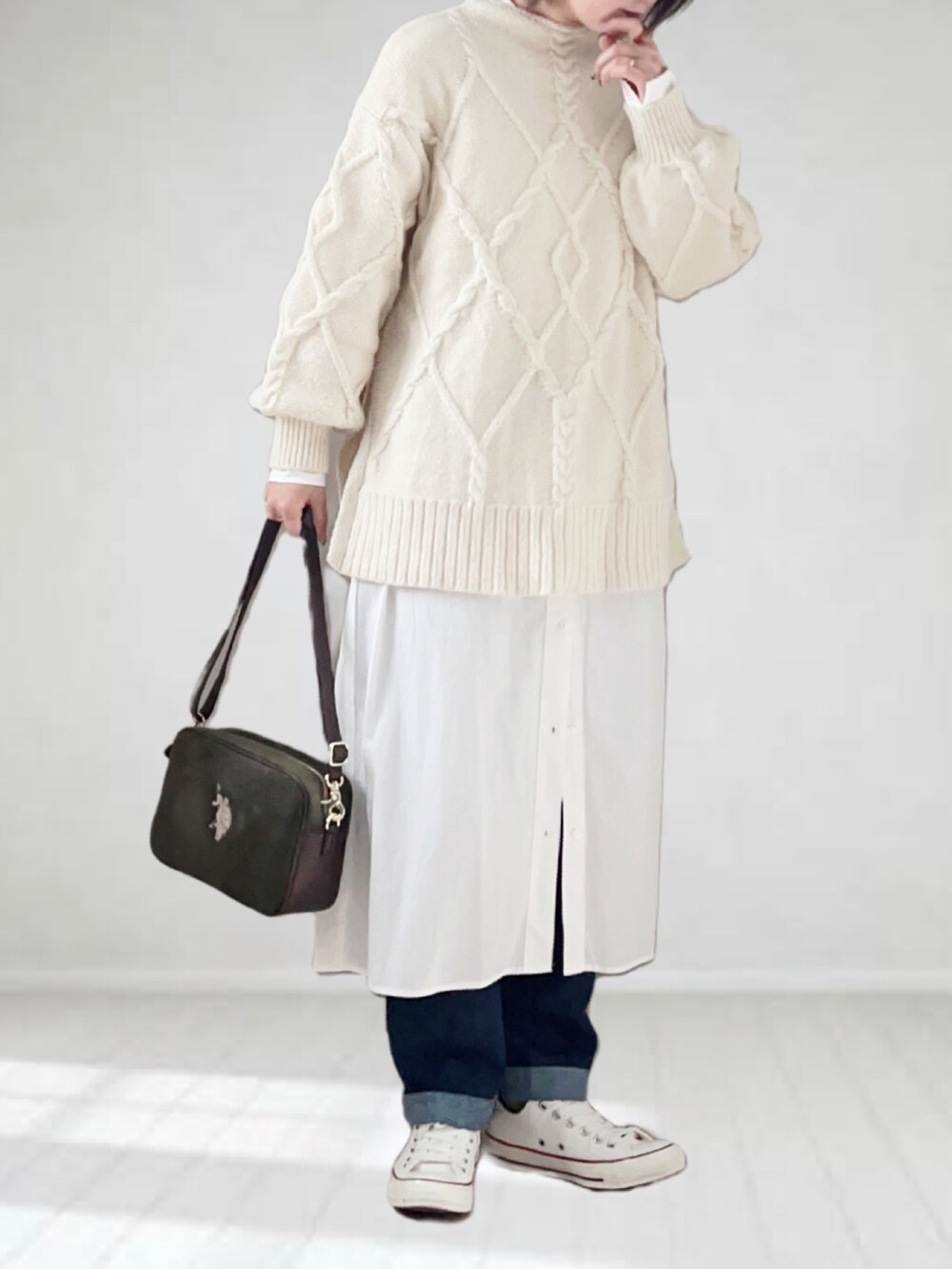 グリーン系のショルダーバッグ、グレー系のワンピース、ブルー系のデニムパンツを着用したレディースの冬コーディネートの3枚目の写真