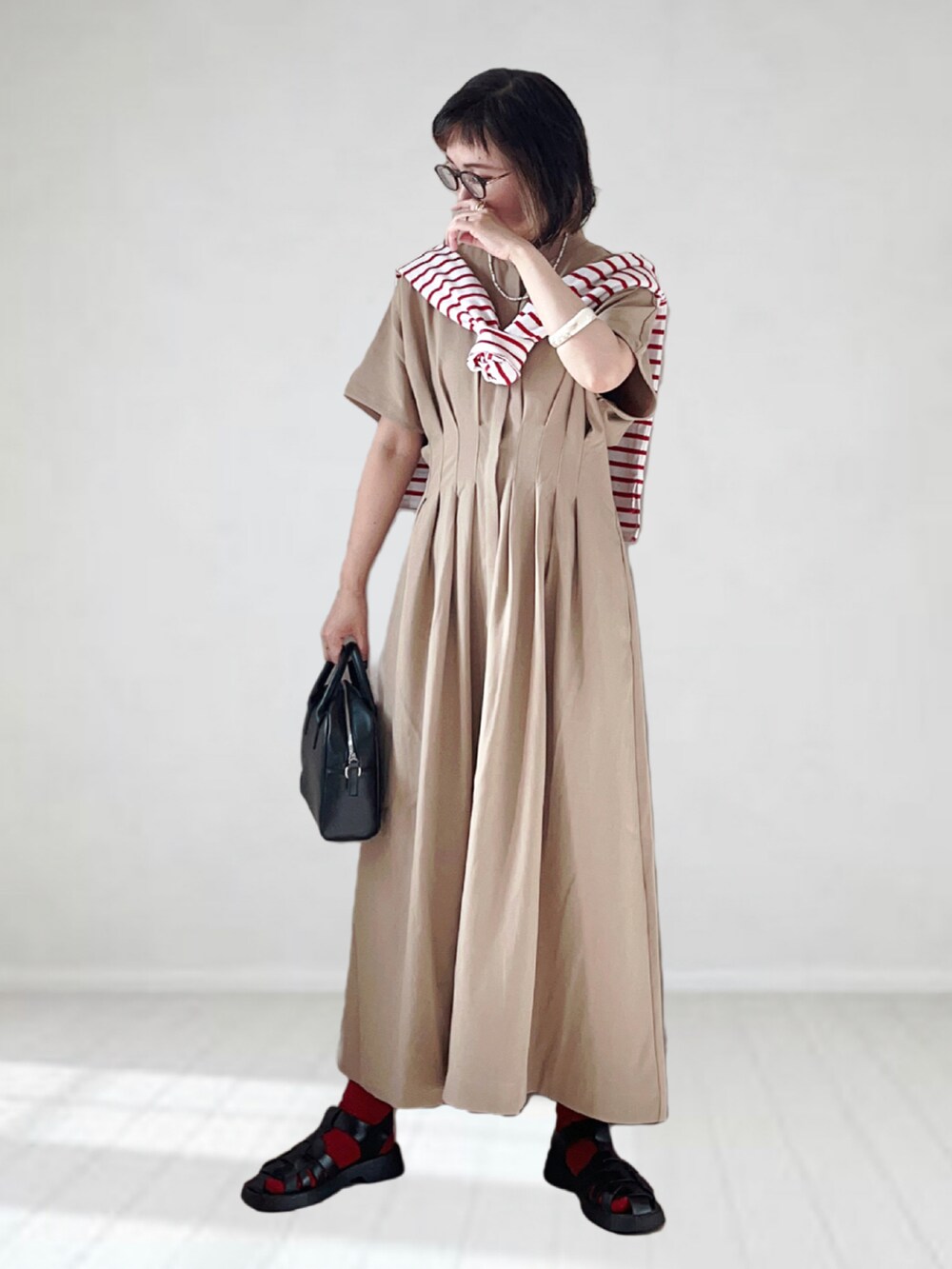ベージュ系のワンピース、ホワイト系のTシャツ/カットソー、ブラック系のボストンバッグを着用したレディースの夏コーディネートの3枚目の写真