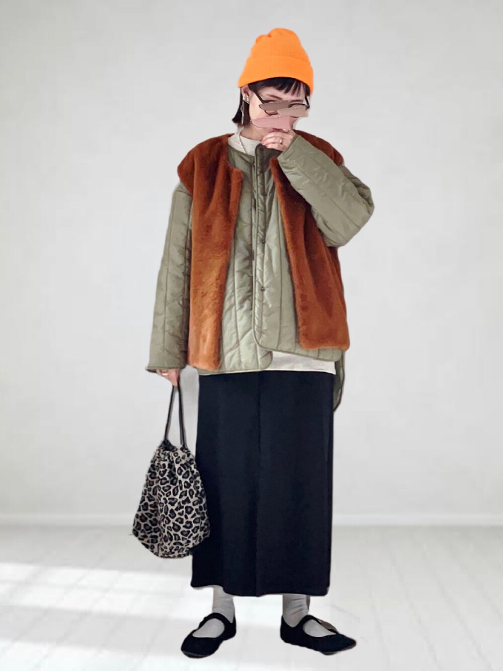 ブラック系のジャンパースカート、イエロー系のベスト、グリーン系のノーカラージャケットを着用したレディースの秋コーディネートの2枚目の写真