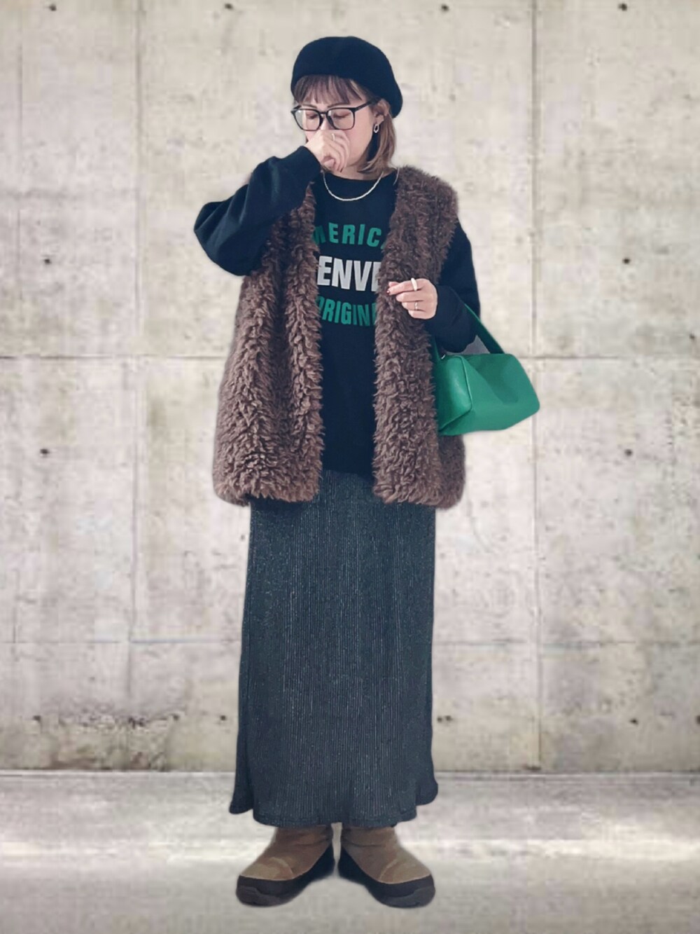 ブラック系のスウェット、ブラウン系のベスト、グレー系のスカートを着用したレディースの冬コーディネートの2枚目の写真