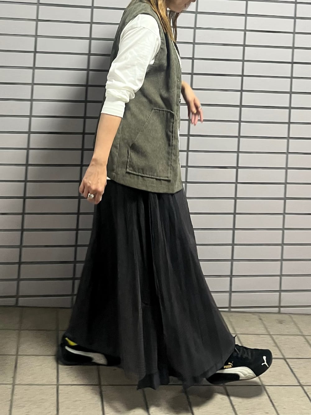 ホワイト系のTシャツ/カットソー、グレー系のスカート、グリーン系のベストを着用したレディースの秋コーディネートの3枚目の写真