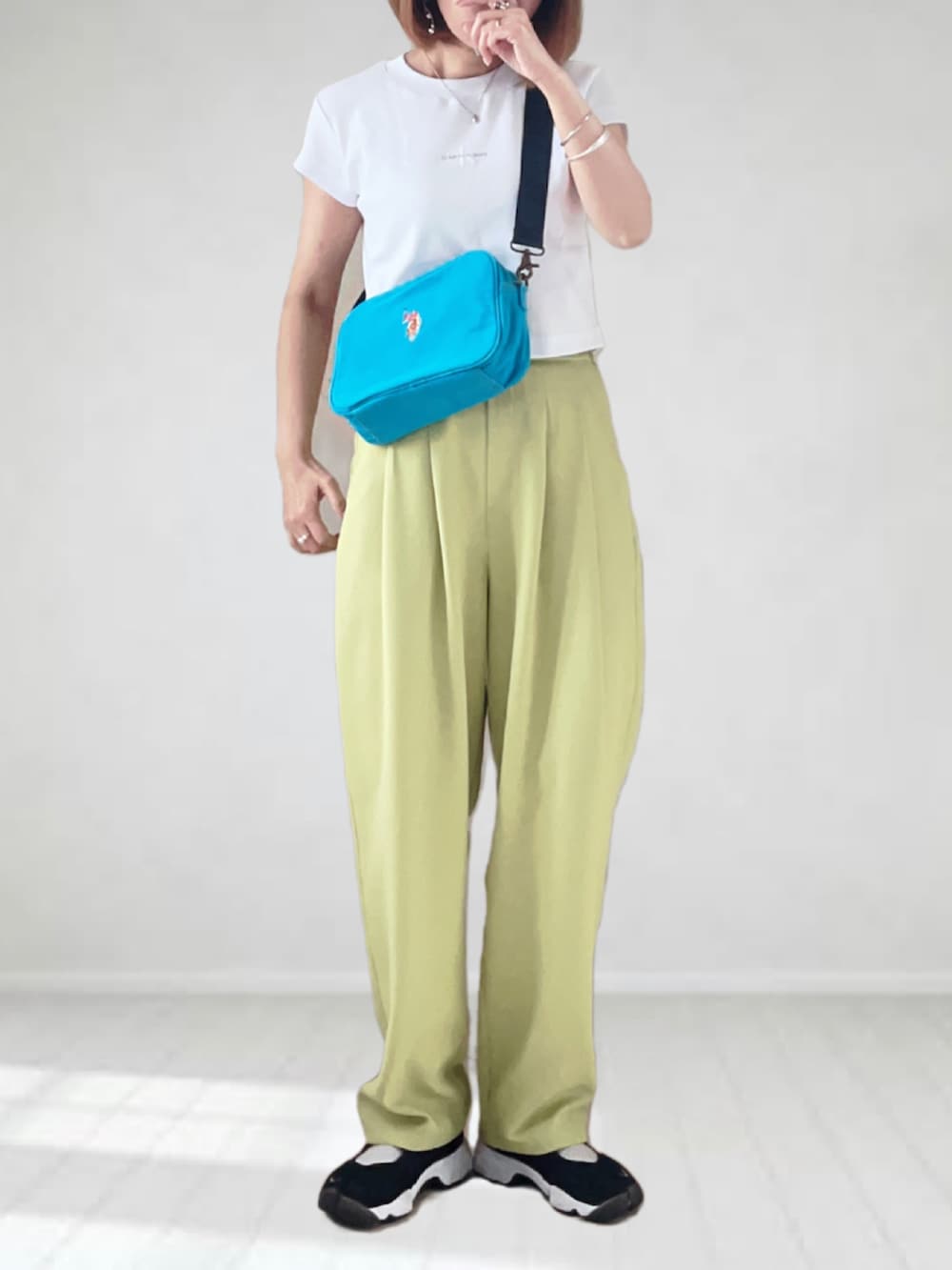 ブルー系のショルダーバッグ、ホワイト系のTシャツ/カットソー、イエロー系のスラックスを着用したレディースの春コーディネートの3枚目の写真