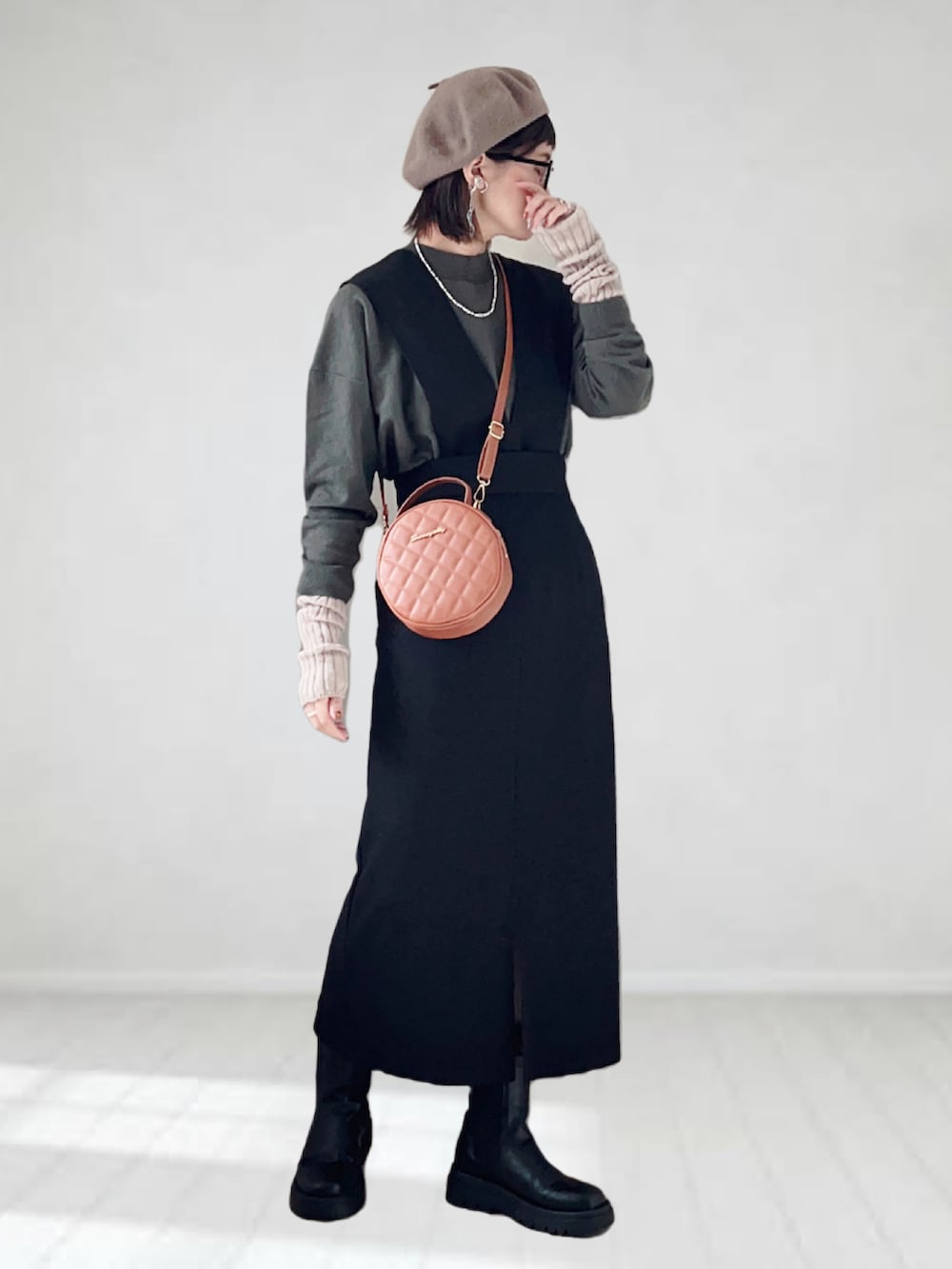 ブラック系のジャンパースカート、ブラック系のニット/セーター、ブラウン系のショルダーバッグを着用したレディースの秋コーディネートの2枚目の写真