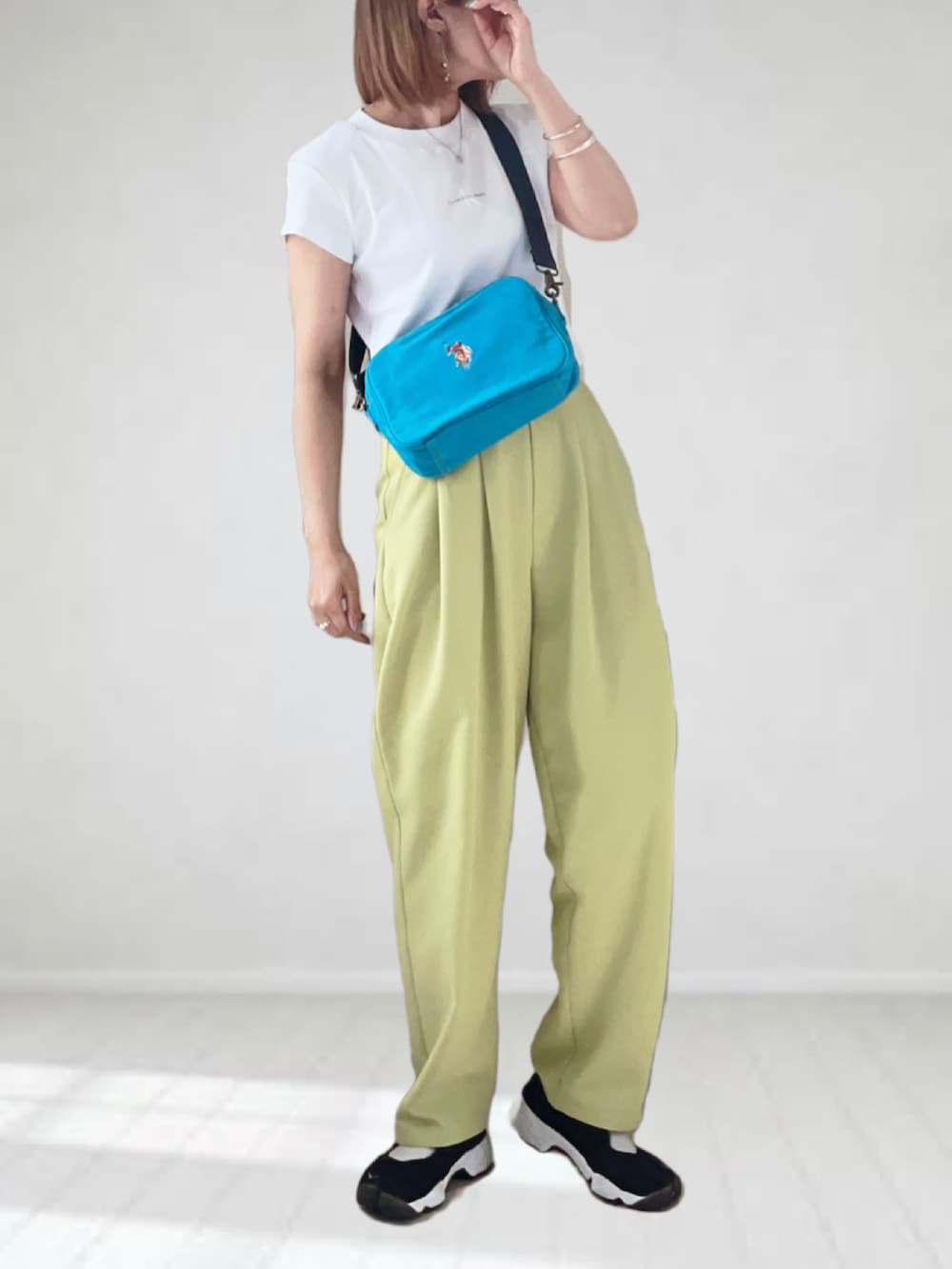 ブルー系のショルダーバッグ、ホワイト系のTシャツ/カットソー、イエロー系のスラックスを着用したレディースの春コーディネートの4枚目の写真