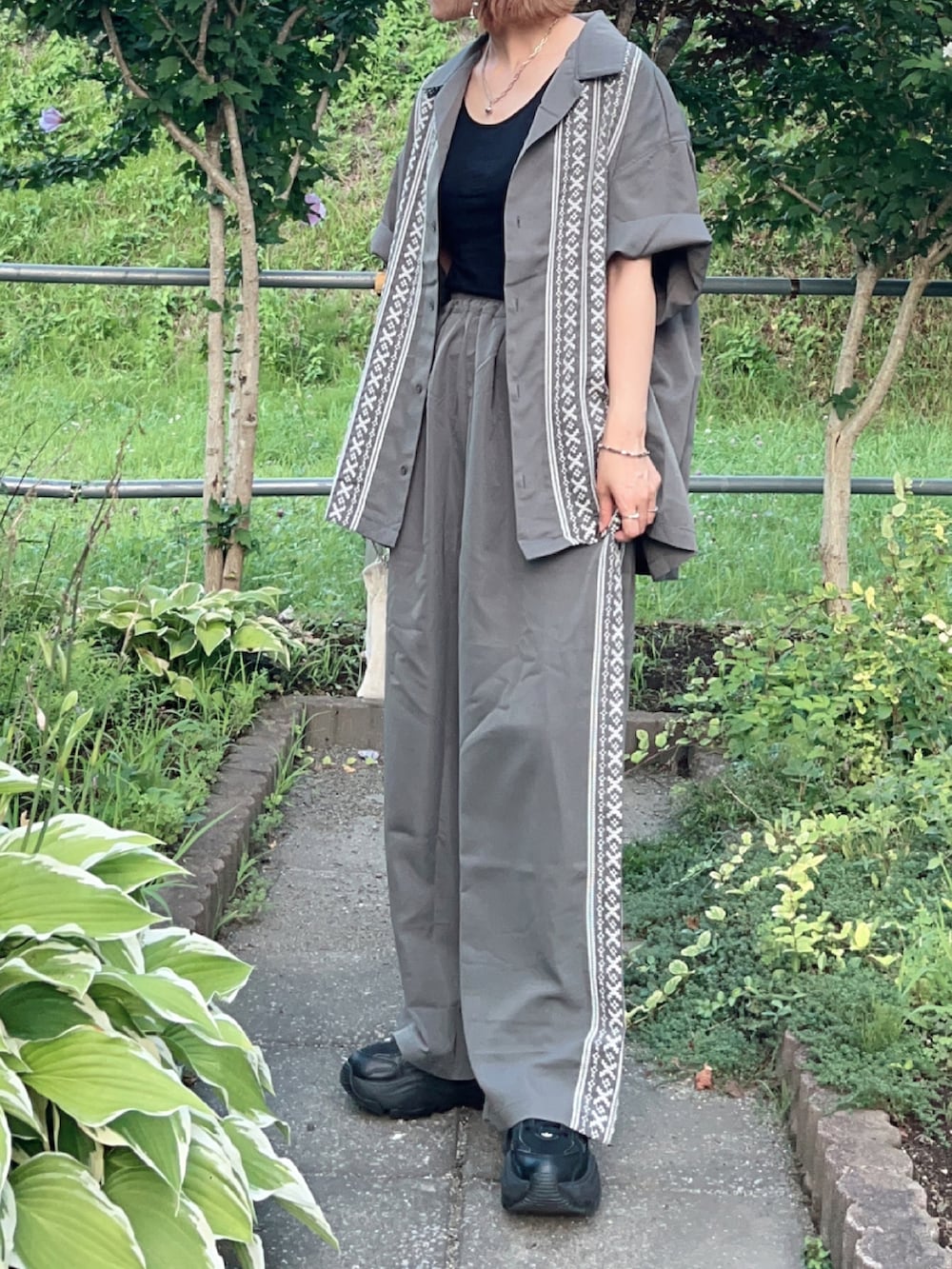 グレー系のシャツ/ブラウス、グレー系のその他パンツ、ブラック系のスニーカーを着用したレディースの夏コーディネートの2枚目の写真