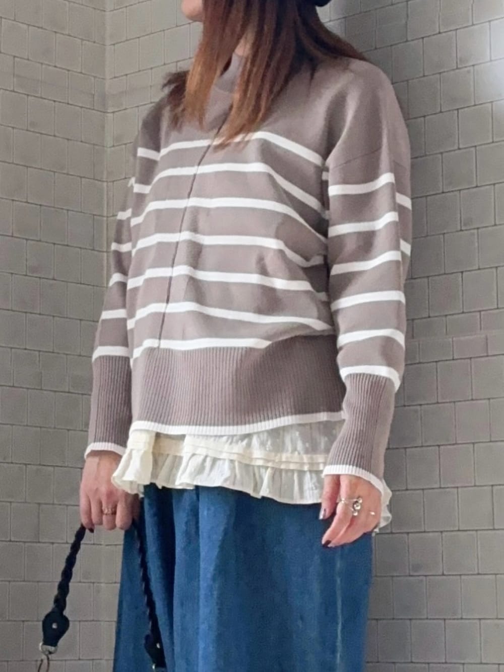 ベージュ系のニット/セーター、ブラック系のショルダーバッグ、ブルー系のデニムパンツを着用したレディースの冬コーディネートの4枚目の写真