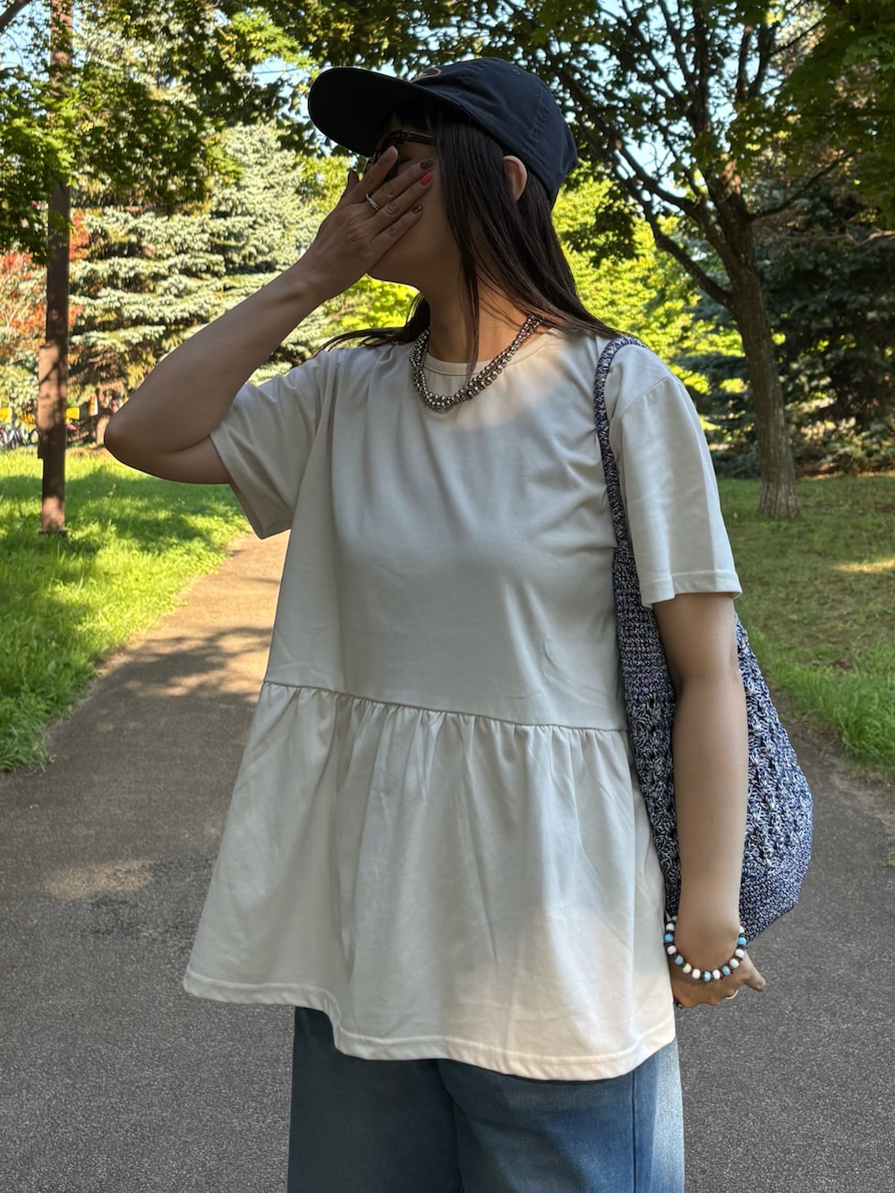 グレー系のTシャツ/カットソー、ブルー系のかごバッグ、ブルー系のデニムパンツを着用したレディースの夏コーディネートの3枚目の写真