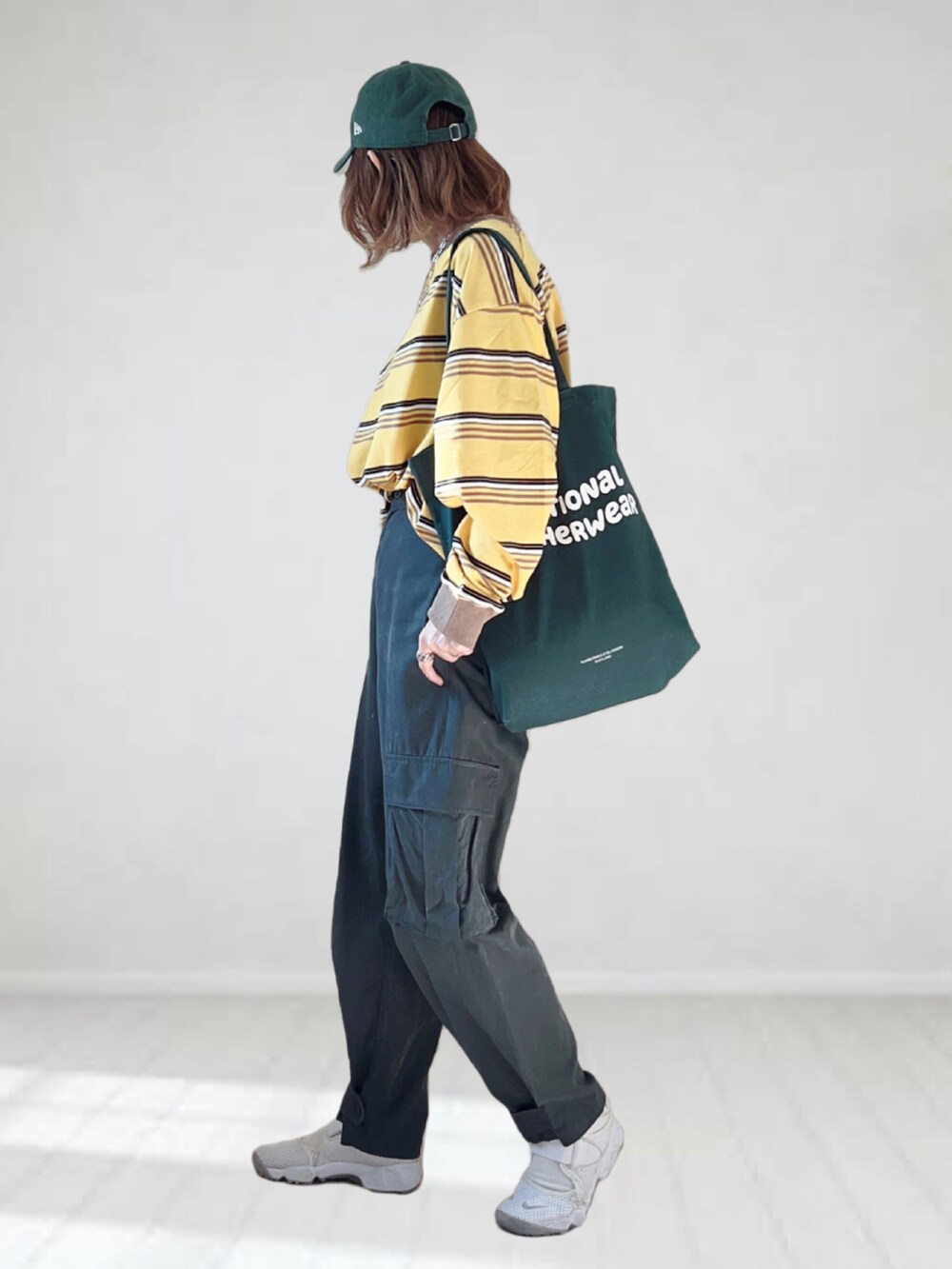 イエロー系のTシャツ/カットソー、グレー系のカーゴパンツ、グリーン系のトートバッグを着用したレディースの春コーディネートの2枚目の写真