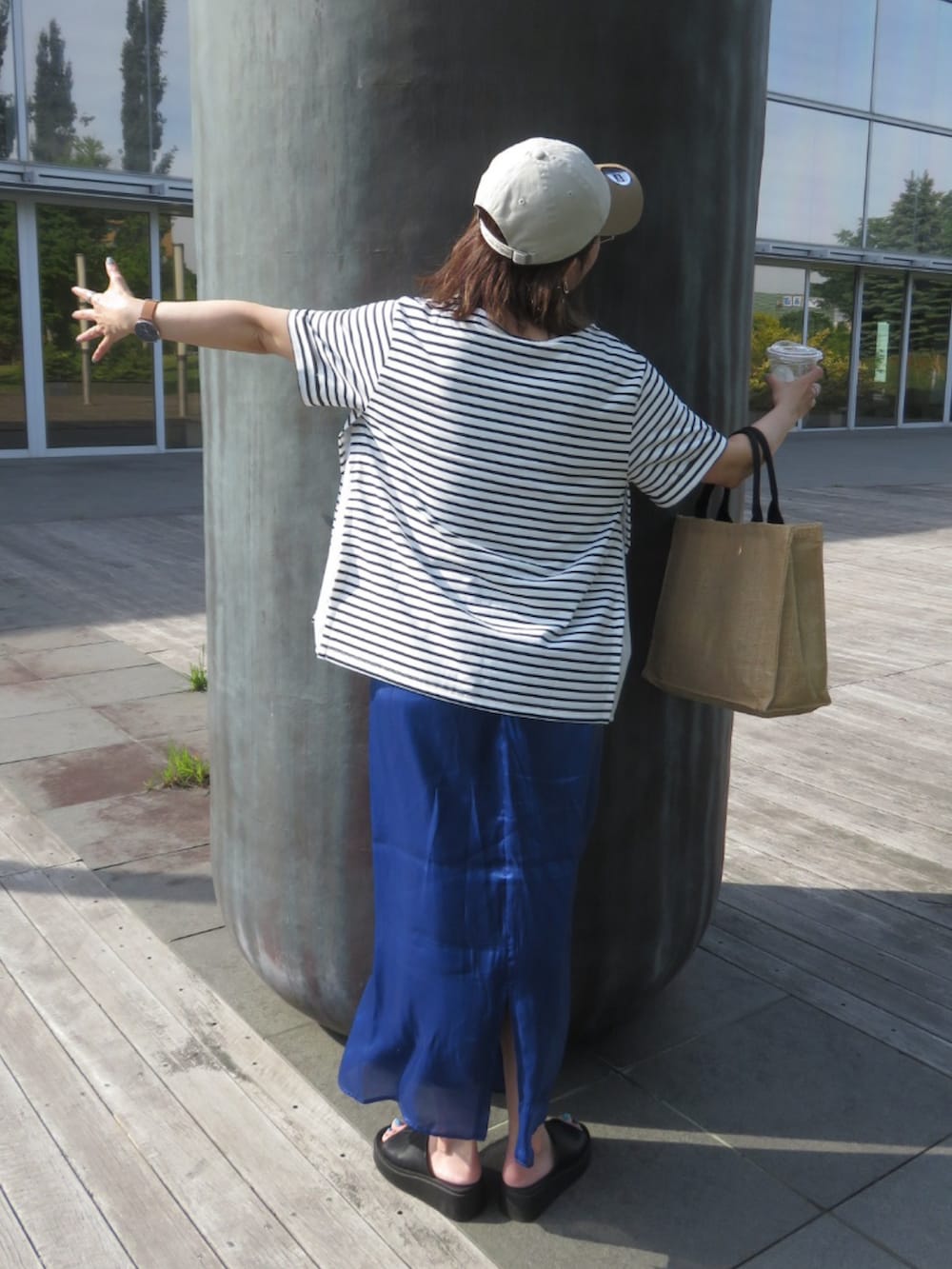 ホワイト系のTシャツ/カットソー、ブルー系のスカート、ブラック系のサンダルを着用したレディースの夏コーディネートの4枚目の写真
