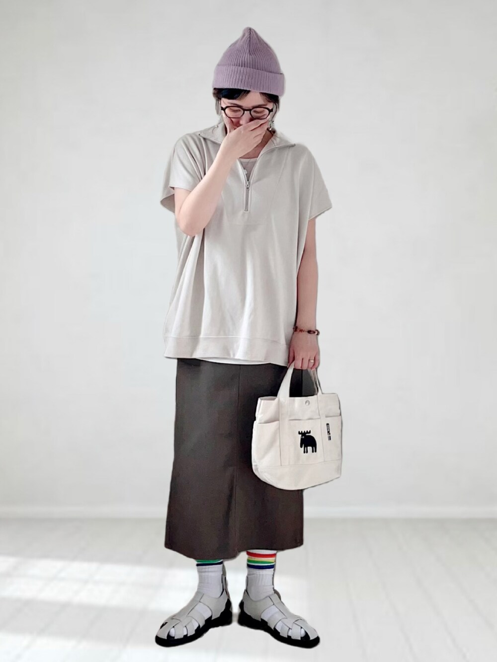 ベージュ系のTシャツ/カットソー、グレー系のスカート、ホワイト系のトートバッグを着用したレディースの春コーディネートの2枚目の写真