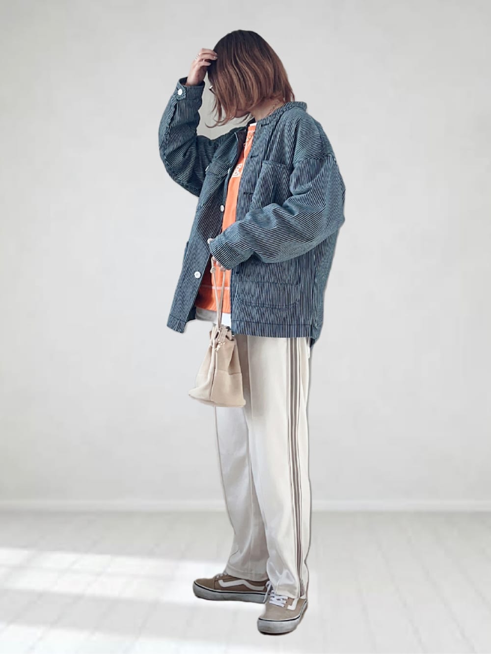 ホワイト系のパンツ、オレンジ系のスウェット、ブルー系のカバーオールを着用したレディースの春コーディネートの2枚目の写真