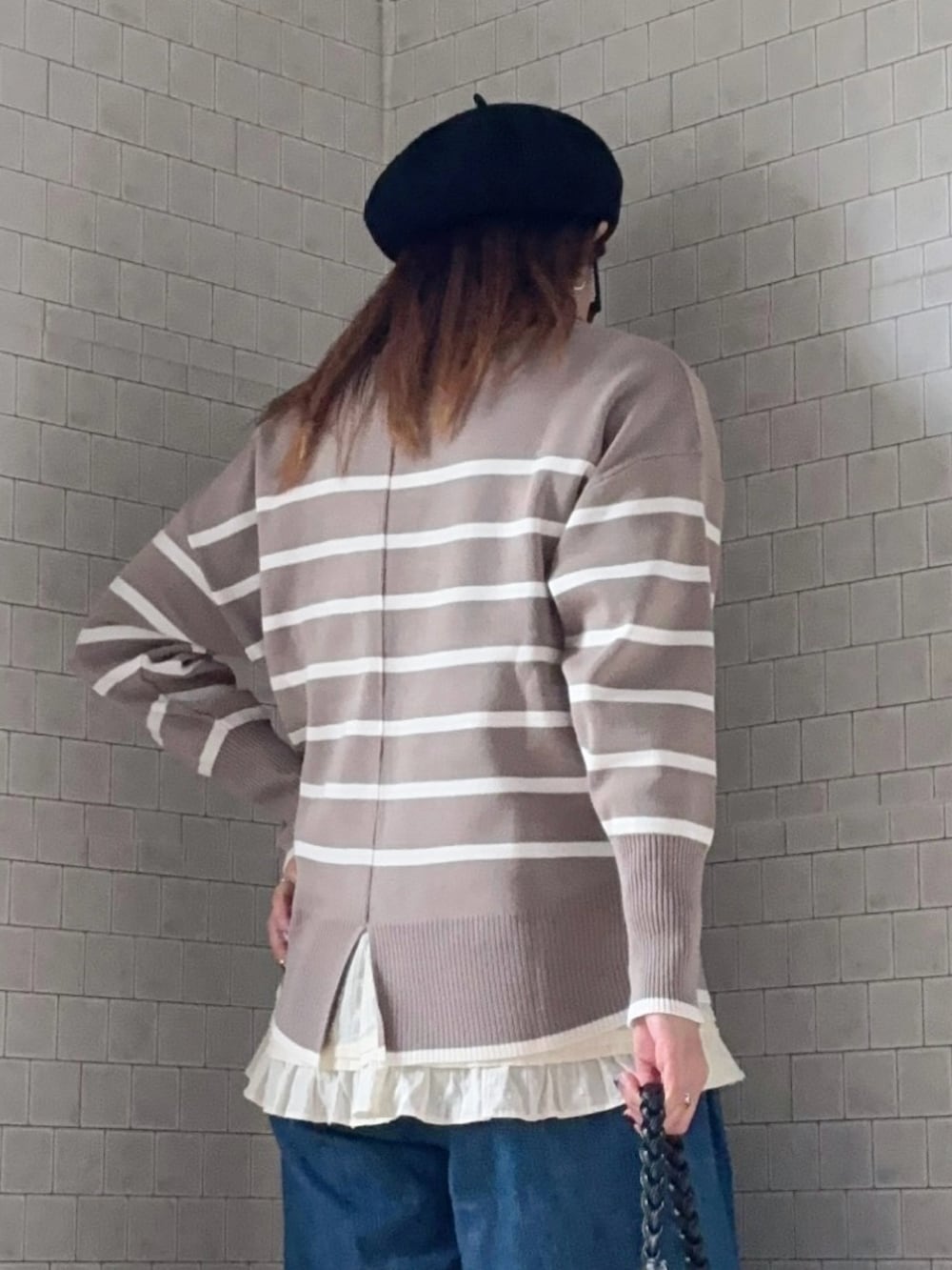 ベージュ系のニット/セーター、ブラック系のショルダーバッグ、ブルー系のデニムパンツを着用したレディースの冬コーディネートの5枚目の写真