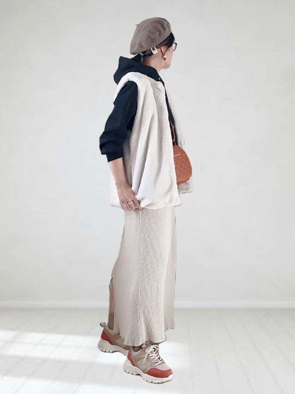 ベージュ系のスニーカー、ブラック系のパーカー、ホワイト系のスカートを着用したレディースの秋コーディネートの2枚目の写真