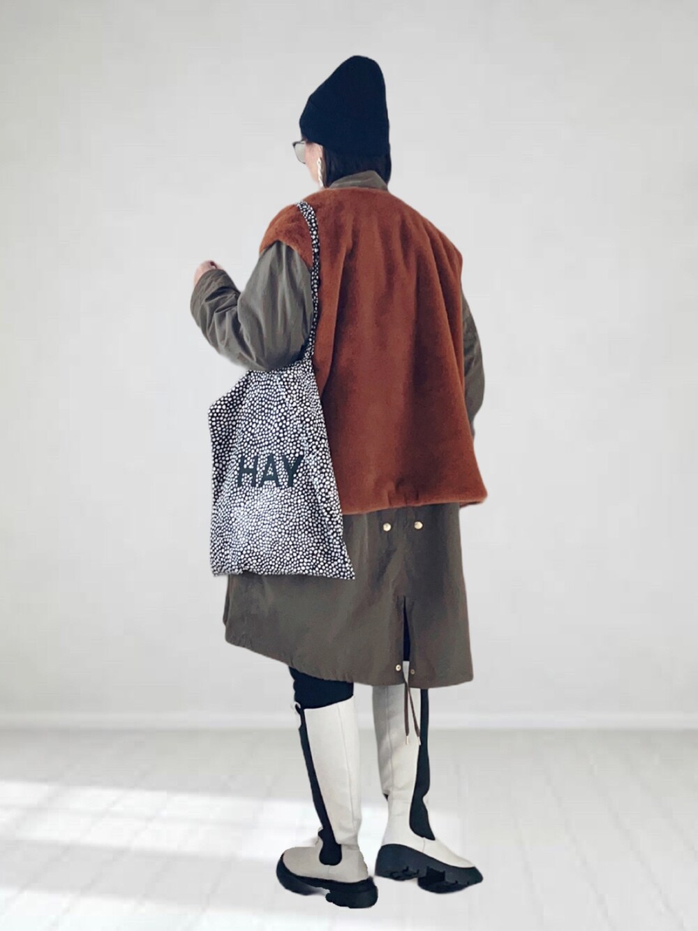 ホワイト系のブーツ、グリーン系のモッズコート、イエロー系のベストを着用したレディースの秋コーディネートの2枚目の写真