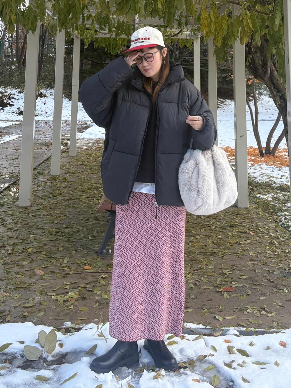 ブラック系のダウンジャケット/コート、ベージュ系のショルダーバッグ、ブラック系のブーツを着用したレディースの冬コーディネートの2枚目の写真