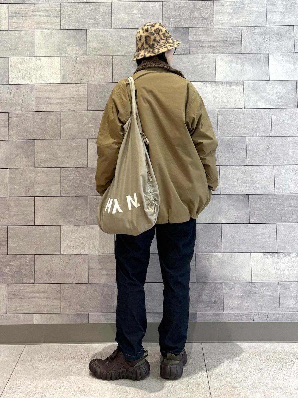 ベージュ系のミリタリージャケット、ホワイト系のスウェット、ブルー系のその他パンツを着用したレディースの春コーディネートの2枚目の写真