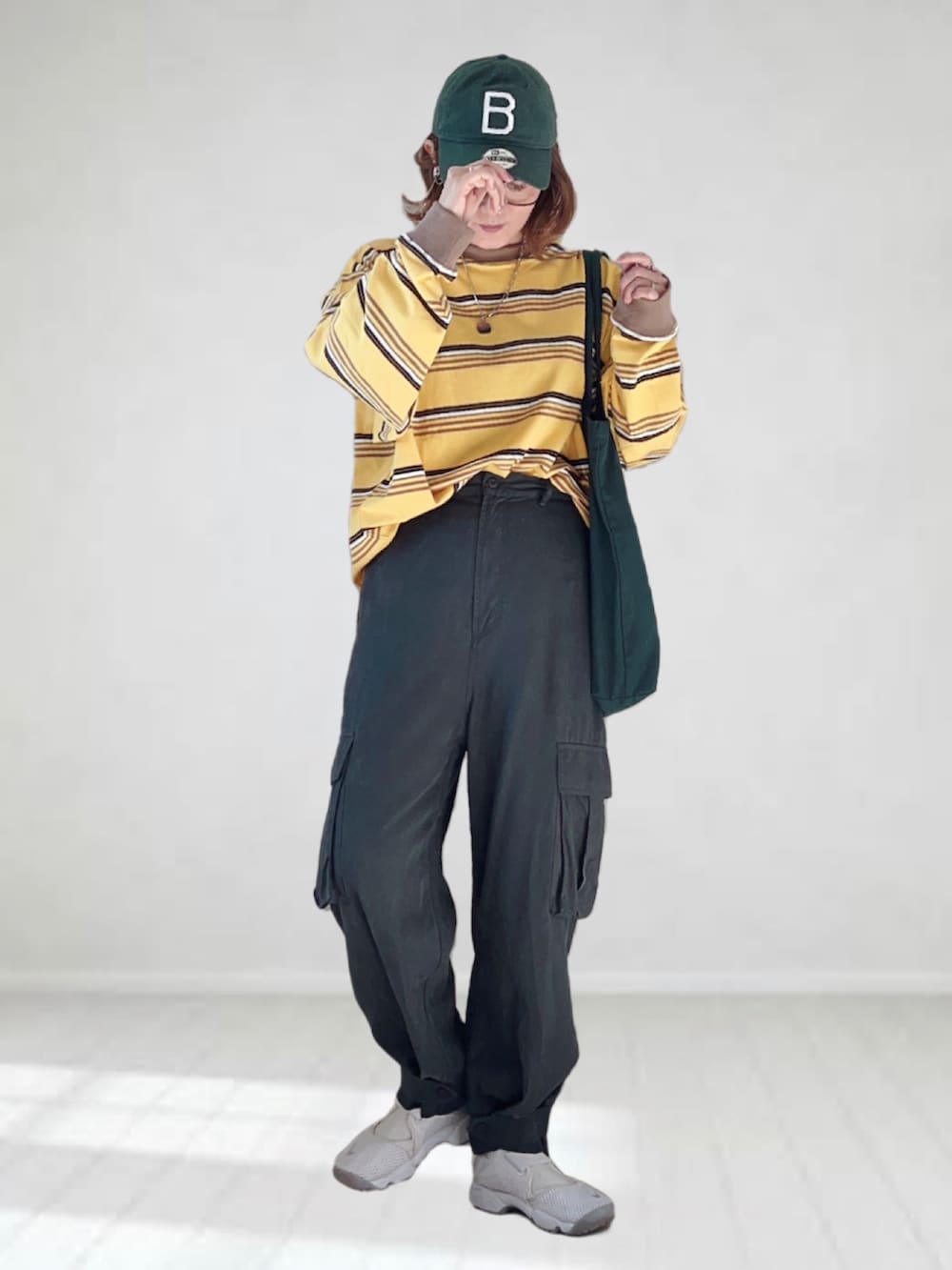 イエロー系のTシャツ/カットソー、グレー系のカーゴパンツ、グリーン系のトートバッグを着用したレディースの春コーディネートの3枚目の写真