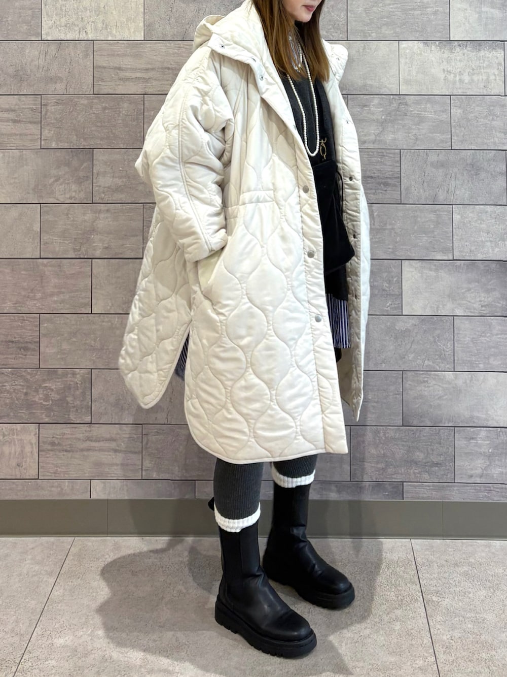 ホワイト系のダウンジャケット/コート、ブラック系のショルダーバッグ、ブラック系のブーツを着用したレディースの秋コーディネートの4枚目の写真