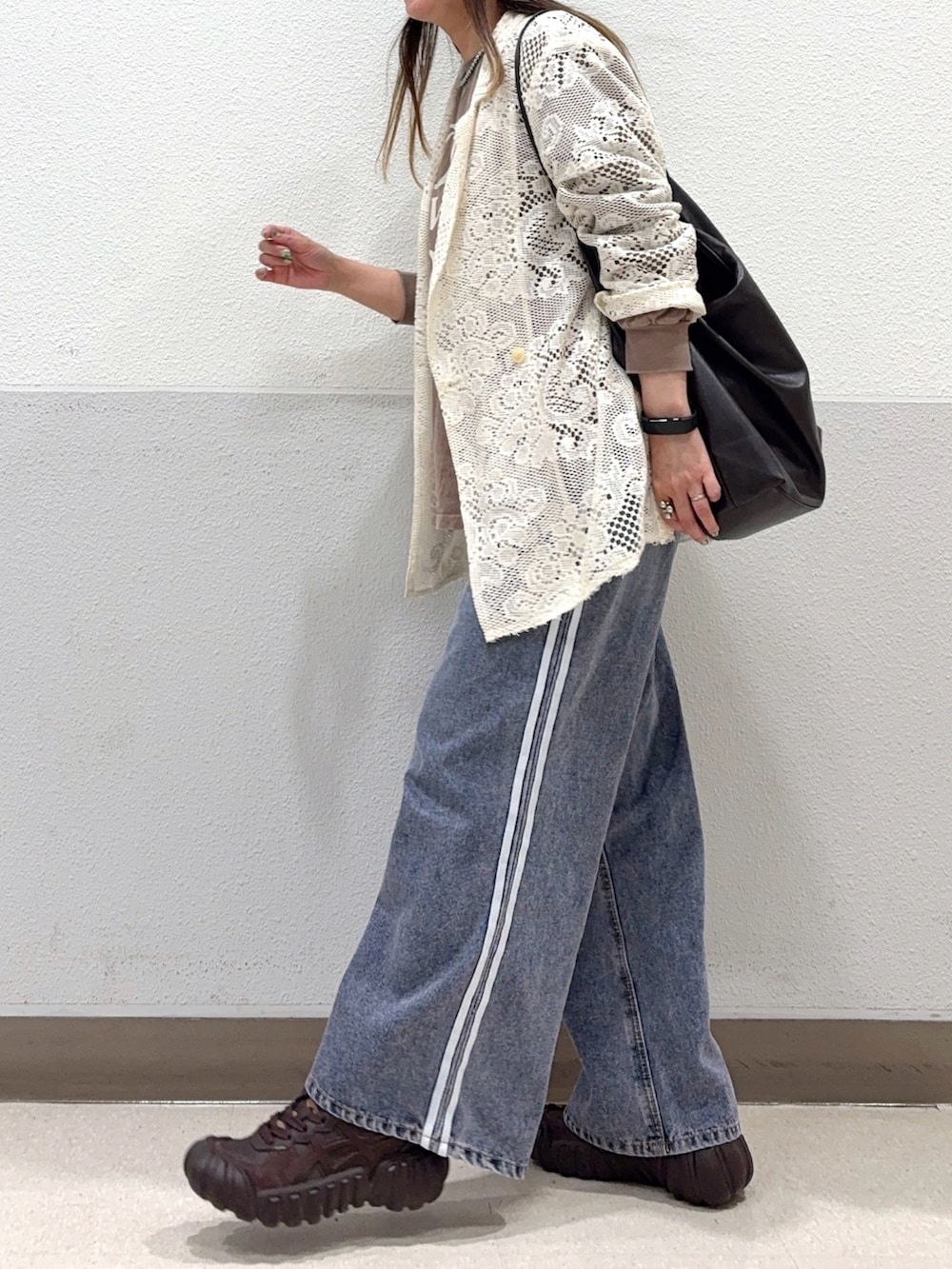ブラウン系のショルダーバッグ、ブルー系のデニムパンツ、ブラウン系のスニーカーを着用したレディースの夏コーディネートの3枚目の写真