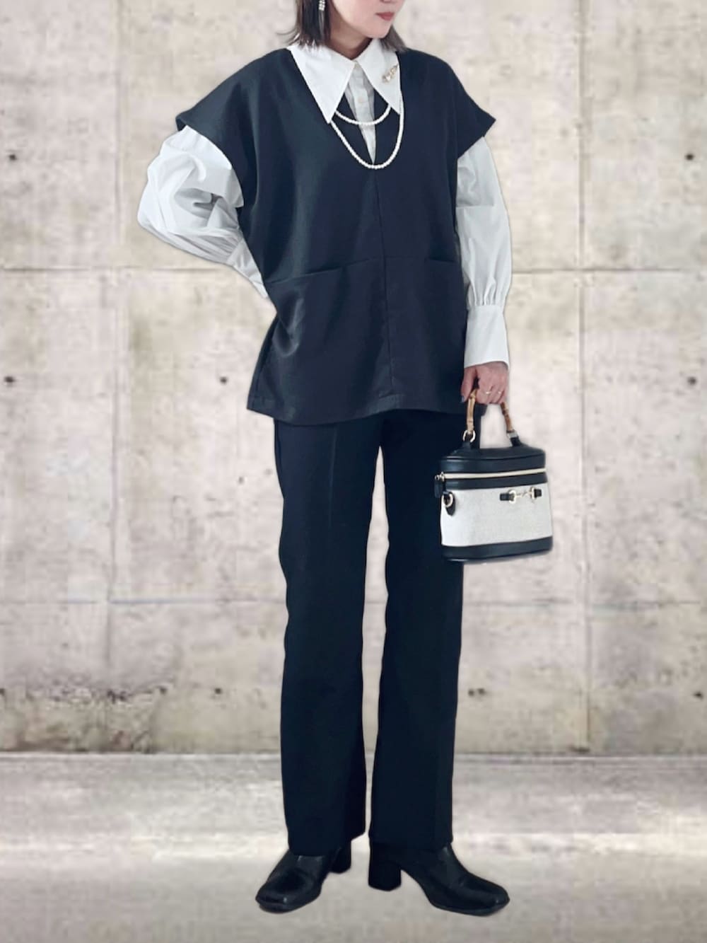 ブラック系のベスト、ホワイト系のシャツ/ブラウス、ブラック系のスラックスを着用したレディースの冬コーディネートの3枚目の写真