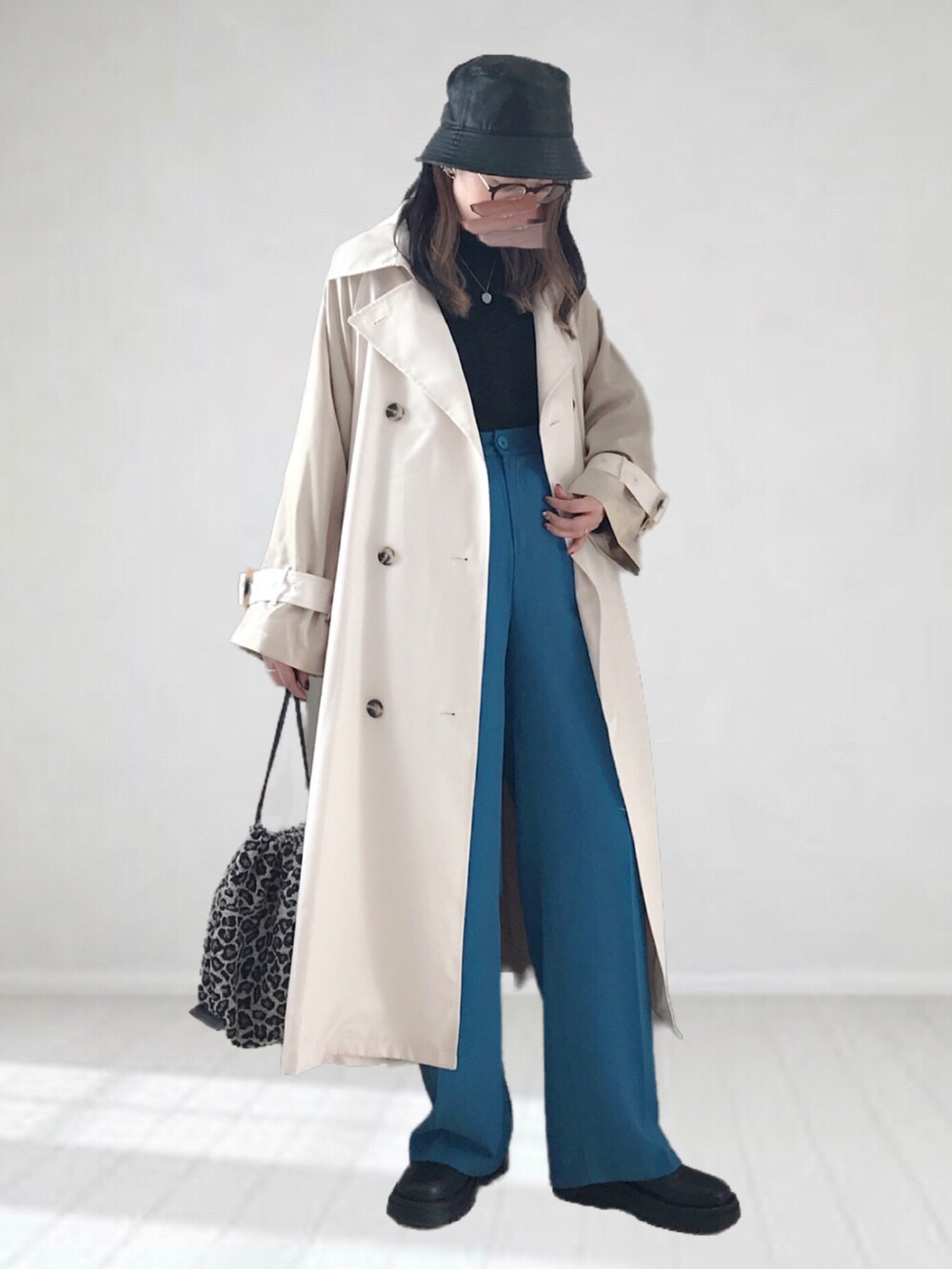 ベージュ系のトレンチコート、ブラック系のニット/セーター、ブルー系のスラックスを着用したレディースの冬コーディネートの2枚目の写真