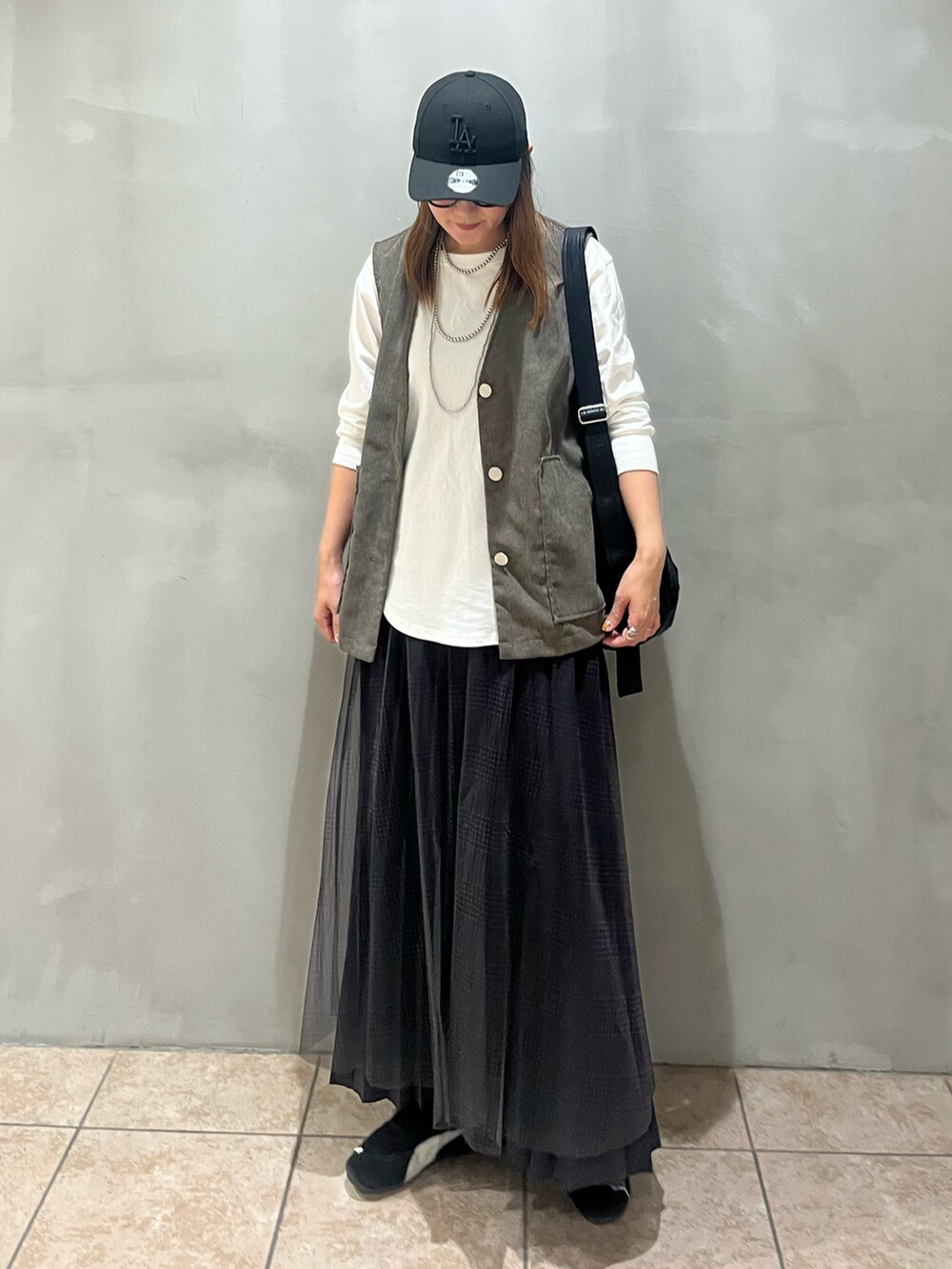 ホワイト系のTシャツ/カットソー、グレー系のスカート、グリーン系のベストを着用したレディースの秋コーディネートの2枚目の写真