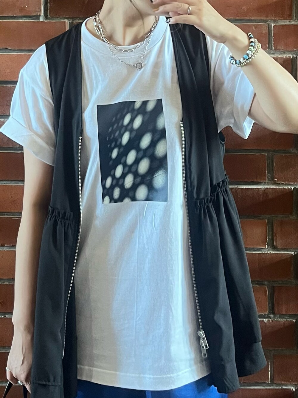 ブラック系のベスト、ブルー系のスカート、ブラック系のサンダルを着用したレディースの夏コーディネートの3枚目の写真