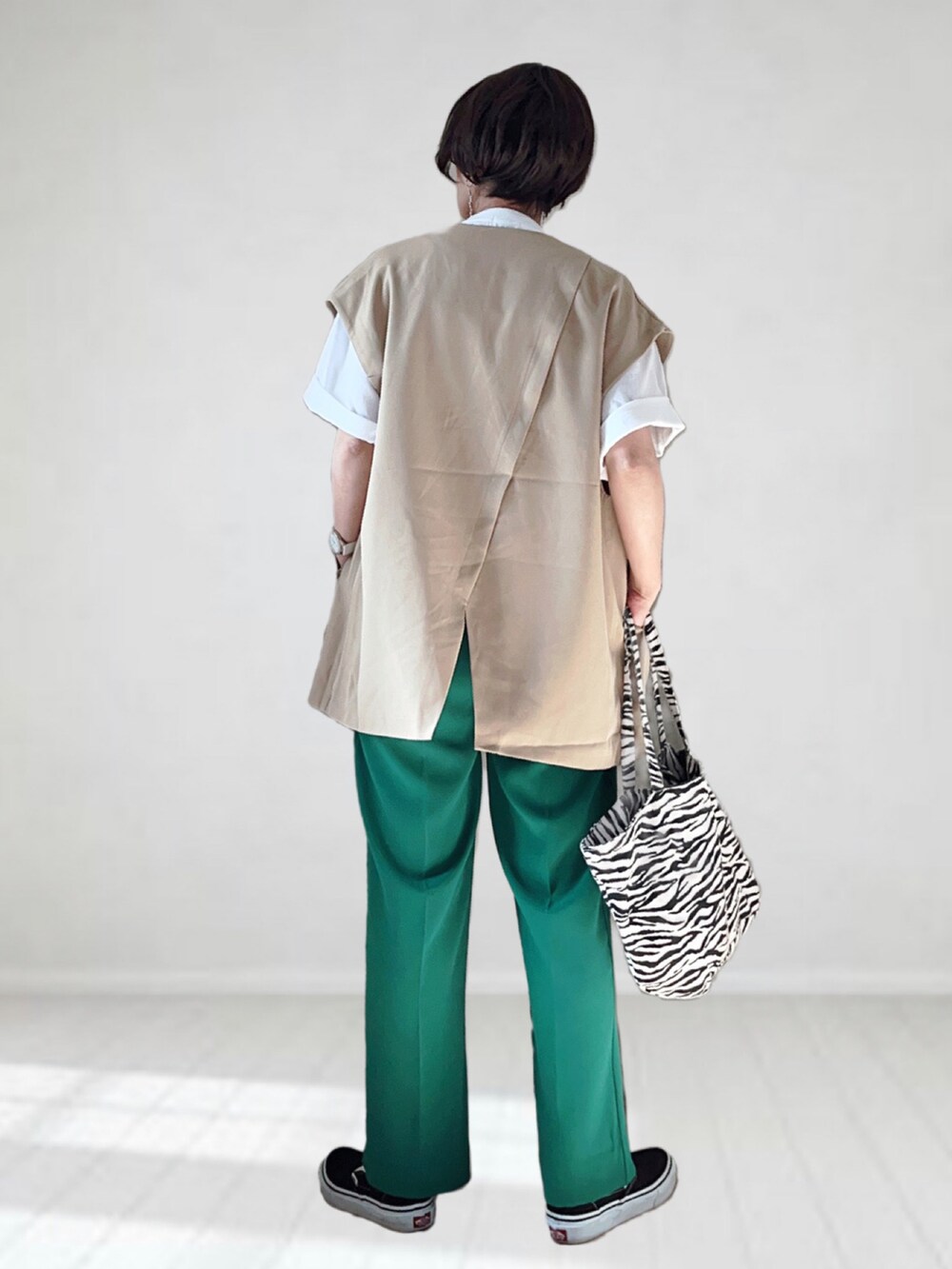 ベージュ系のベスト、ホワイト系のTシャツ/カットソー、グリーン系のスラックスを着用したレディースの春コーディネートの3枚目の写真