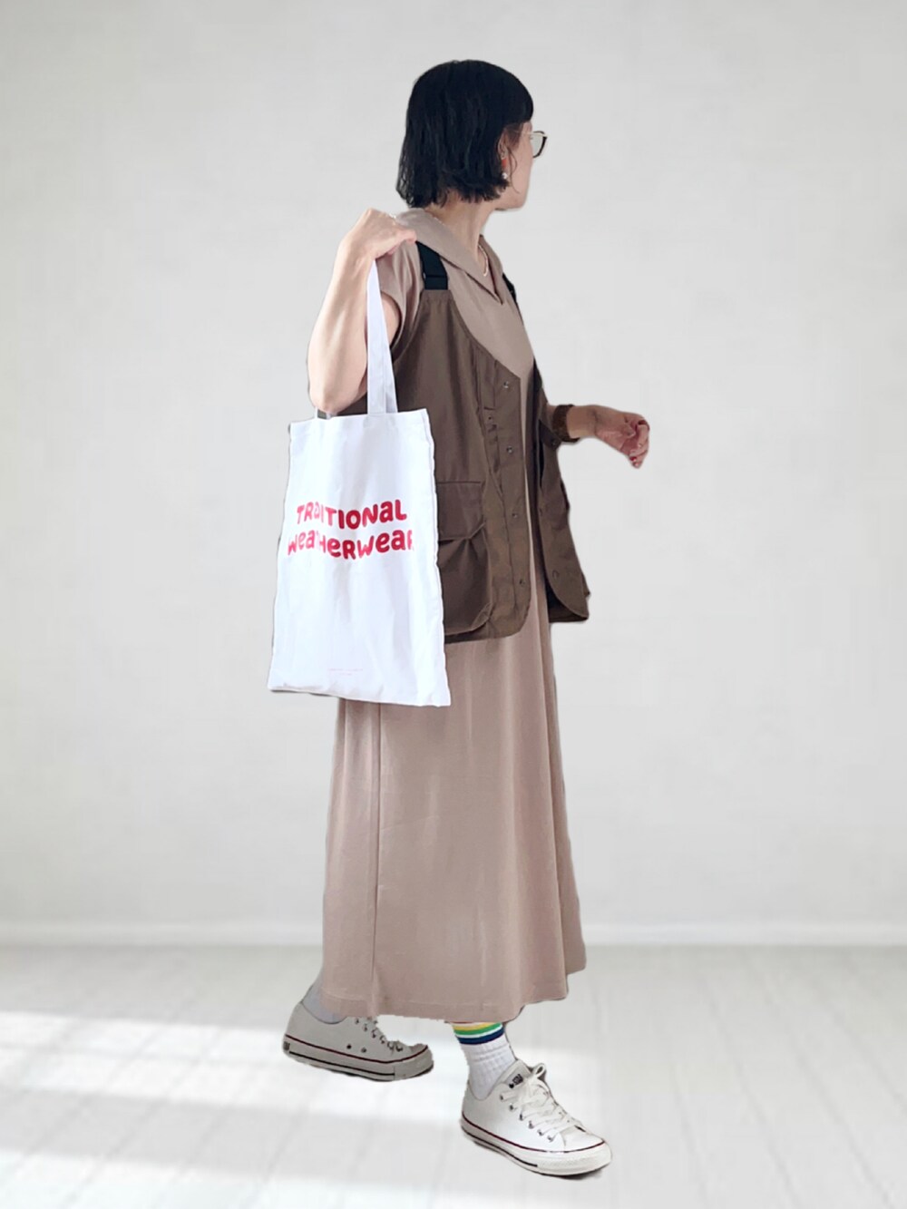 ベージュ系のワンピース、ブラウン系のベスト、レッド系のトートバッグを着用したレディースの夏コーディネートの3枚目の写真