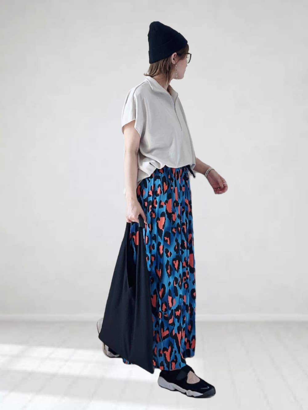 ブルー系のスカート、ベージュ系のTシャツ/カットソー、ブラック系のトートバッグを着用したレディースの夏コーディネートの2枚目の写真