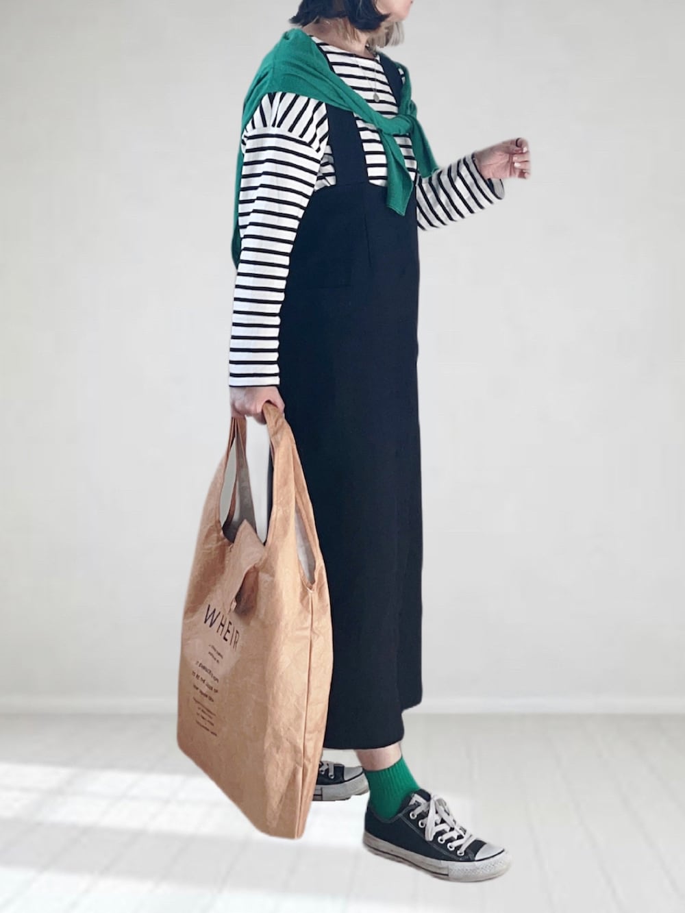 ブラック系のジャンパースカート、グリーン系のカーディガン/ボレロ、ホワイト系のTシャツ/カットソーを着用したレディースの春コーディネートの2枚目の写真