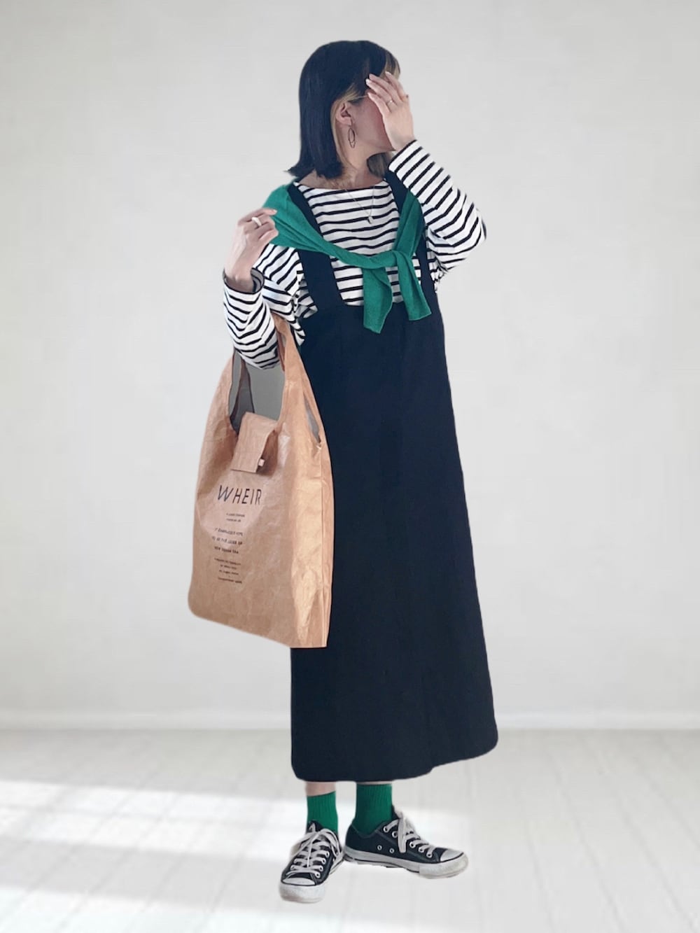 ブラック系のジャンパースカート、グリーン系のカーディガン/ボレロ、ホワイト系のTシャツ/カットソーを着用したレディースの春コーディネートの3枚目の写真