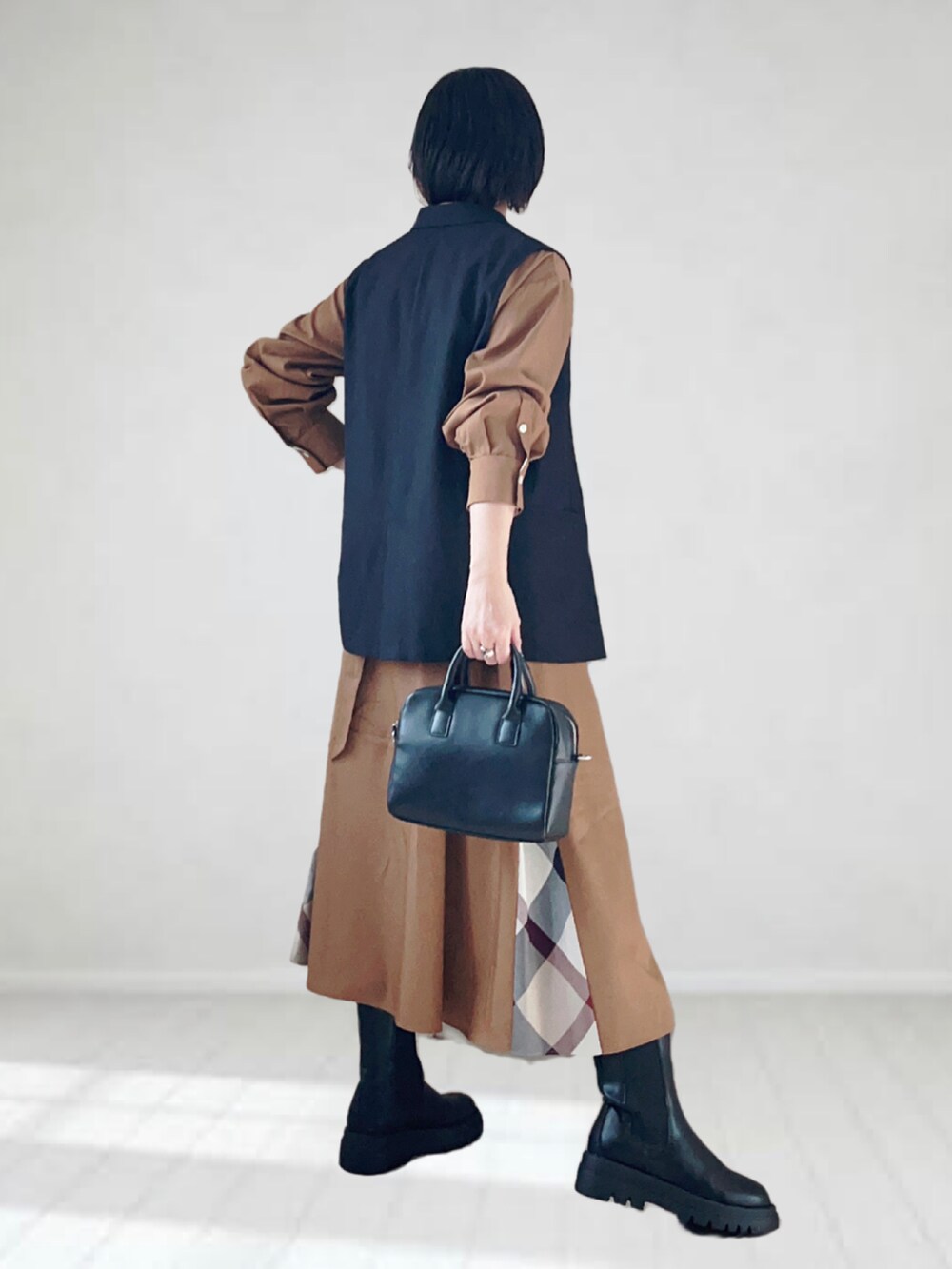 ベージュ系のワンピース、ブラック系のベスト、ブラック系のボストンバッグを着用したレディースの秋コーディネートの3枚目の写真