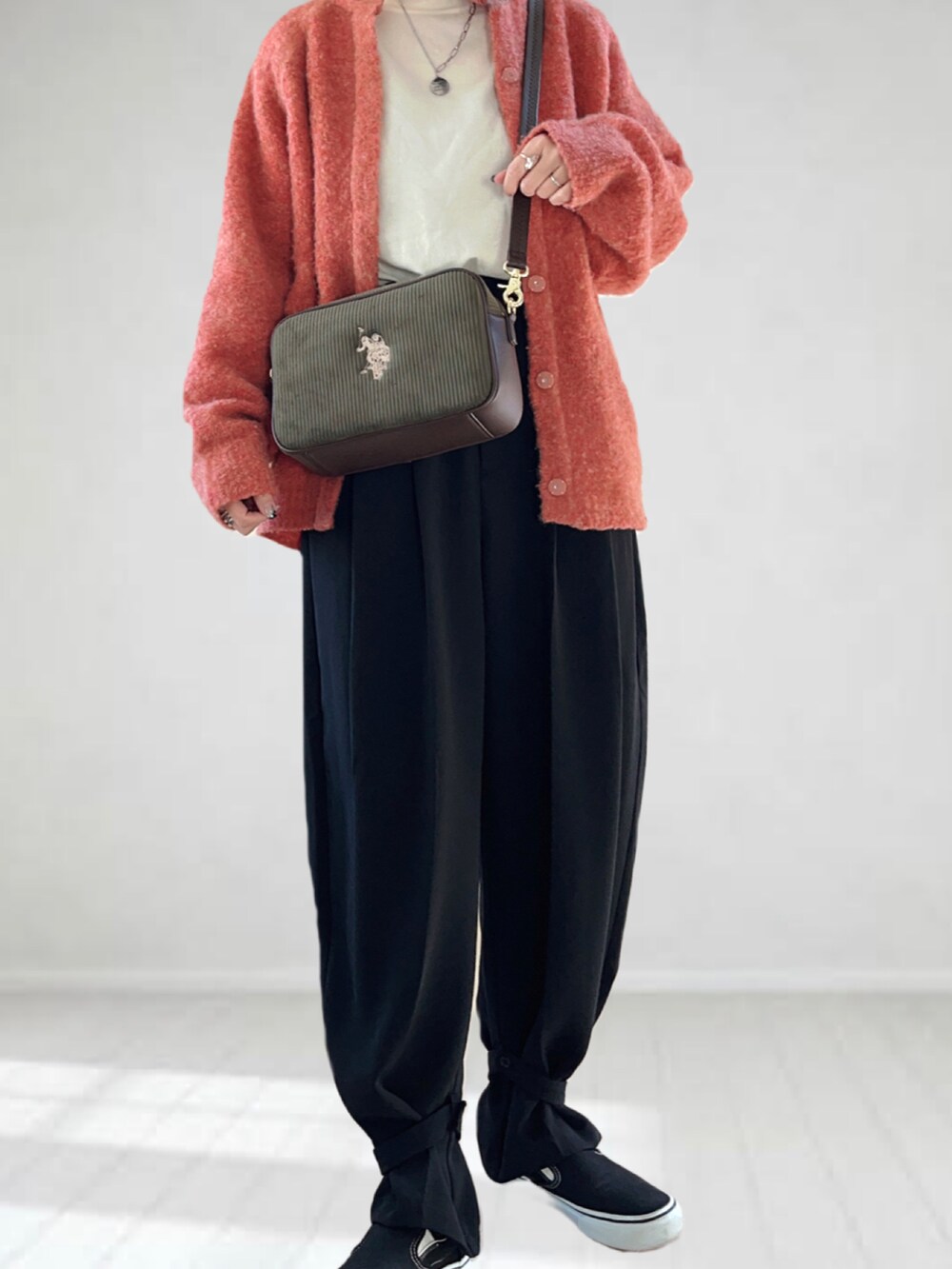 グリーン系のショルダーバッグ、ピンク系のカーディガン/ボレロ、ホワイト系のニット/セーターを着用したレディースの冬コーディネートの2枚目の写真