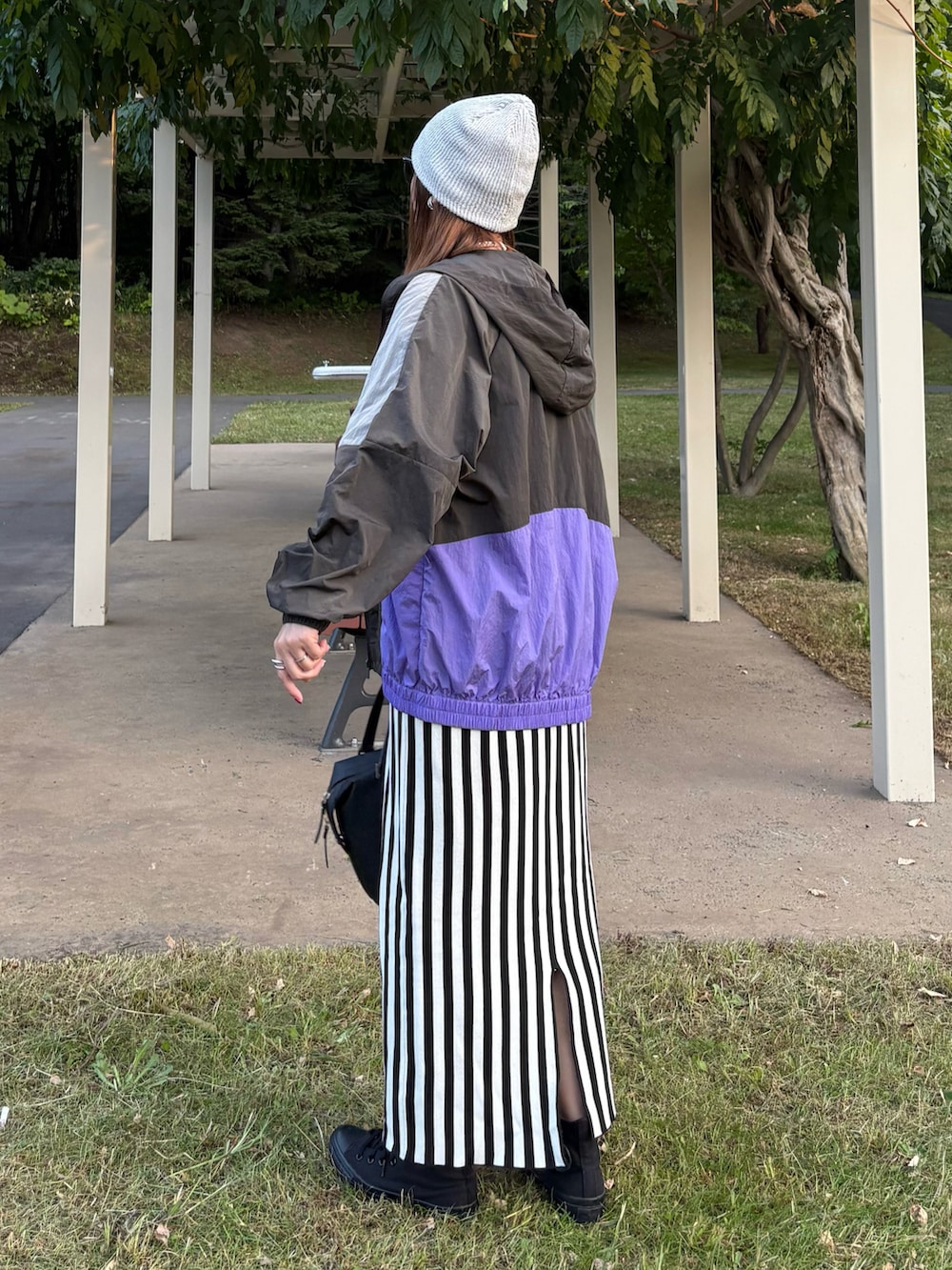 ブラック系のマウンテンパーカー、ホワイト系のスカート、ブラック系のスニーカーを着用したレディースの秋コーディネートの3枚目の写真