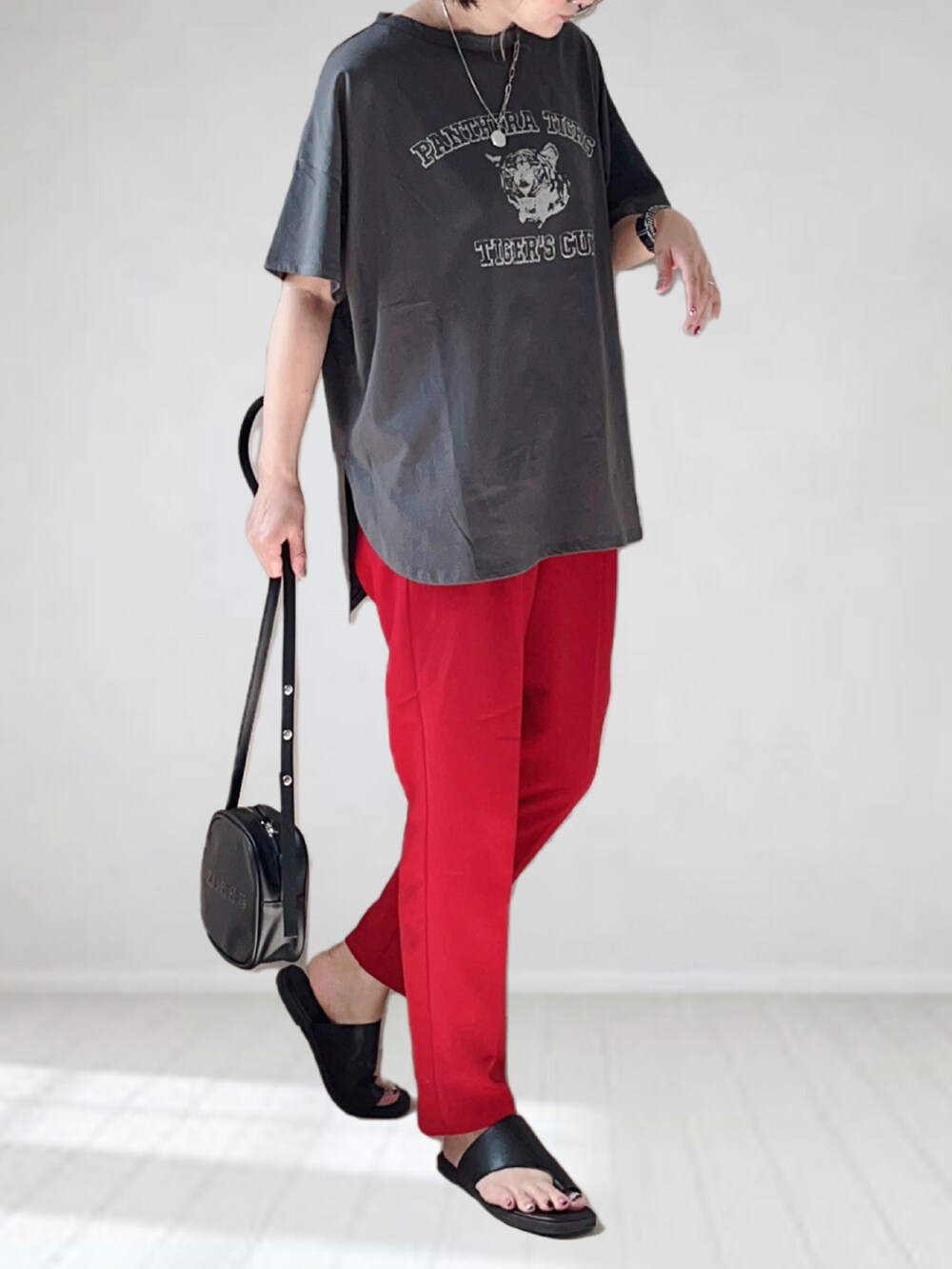 グレー系のTシャツ/カットソー、レッド系のスラックス、ブラック系のショルダーバッグを着用したレディースの夏コーディネートの3枚目の写真
