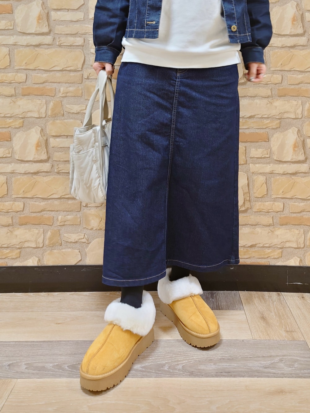 ブルー系のブルゾン、ホワイト系のトートバッグ、イエロー系のブーツを着用したレディースの冬コーディネートの3枚目の写真