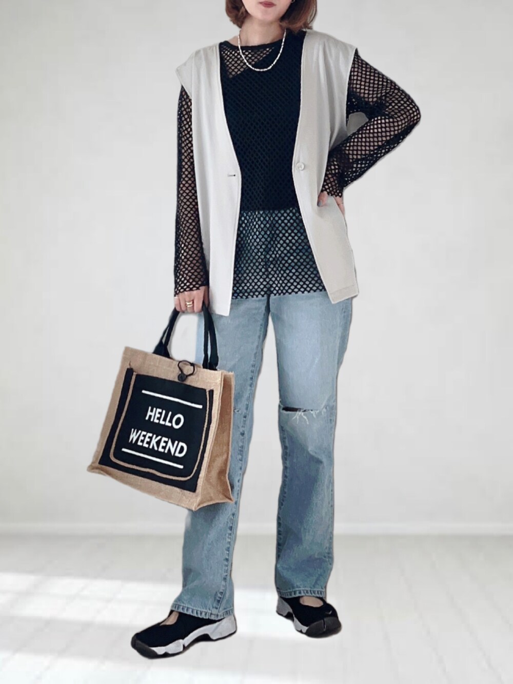 ブルー系のデニムパンツ、ベージュ系のベスト、ブラック系のTシャツ/カットソーを着用したレディースの春コーディネートの2枚目の写真