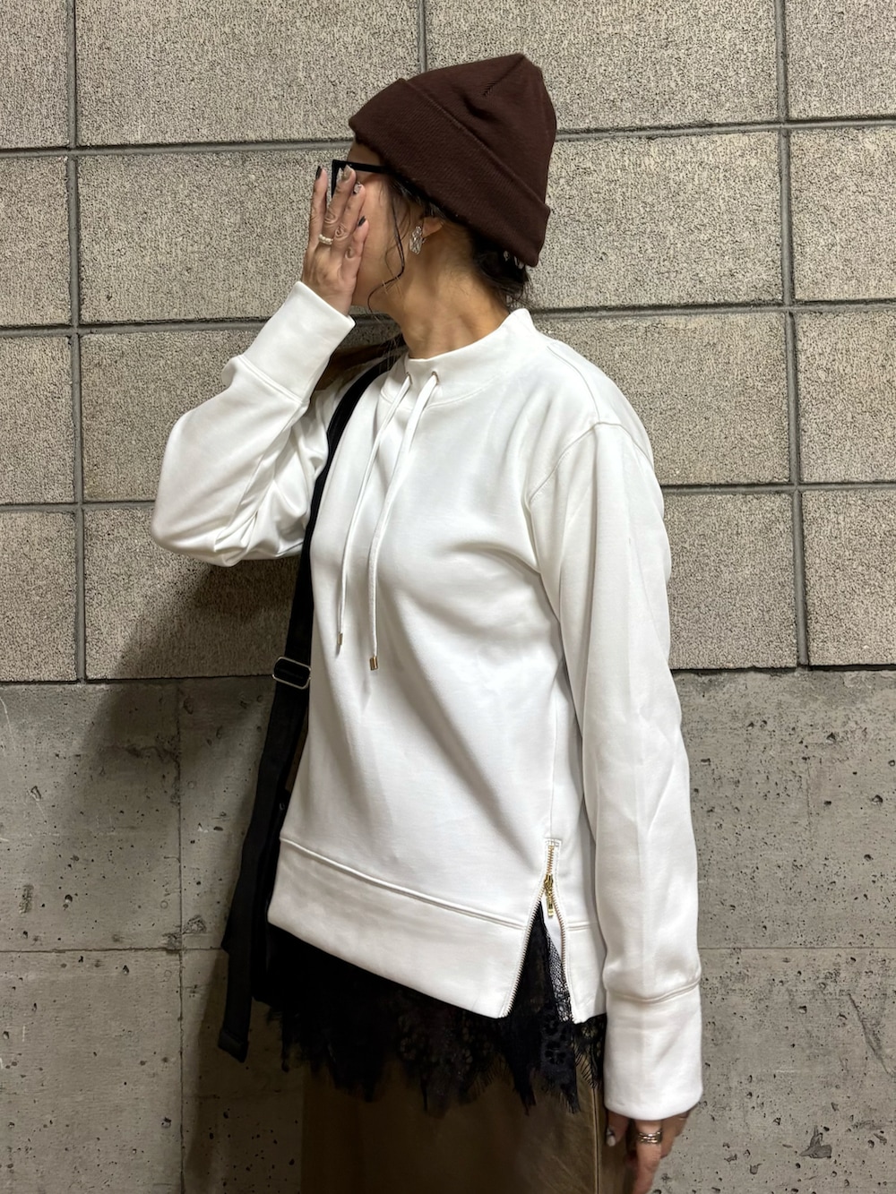 ホワイト系のスウェット、ブラウン系のスニーカー、ブラック系のショルダーバッグを着用したレディースの春コーディネートの5枚目の写真