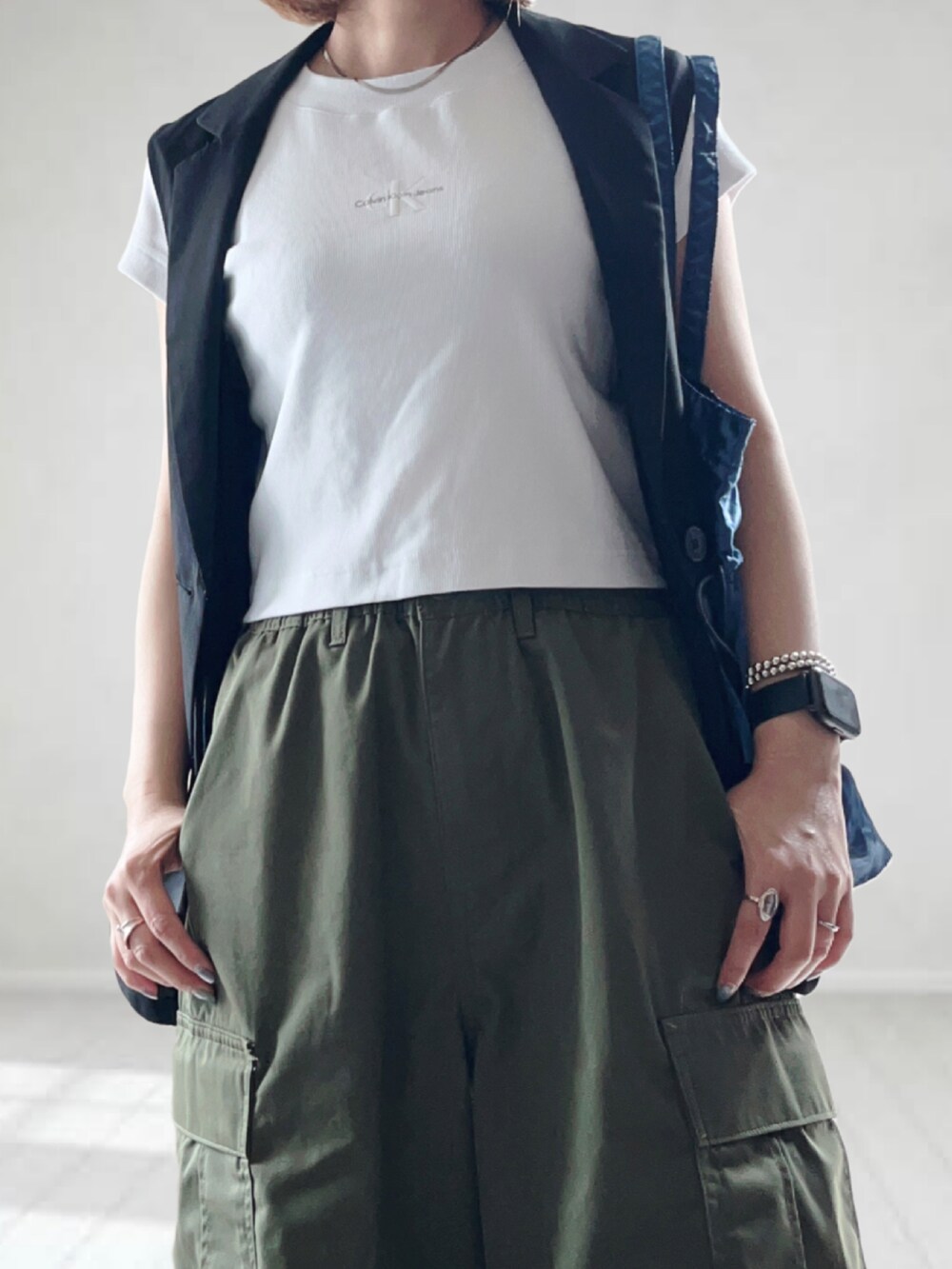 ホワイト系のTシャツ/カットソー、ブラック系のベスト、グリーン系のカーゴパンツを着用したレディースの春コーディネートの2枚目の写真